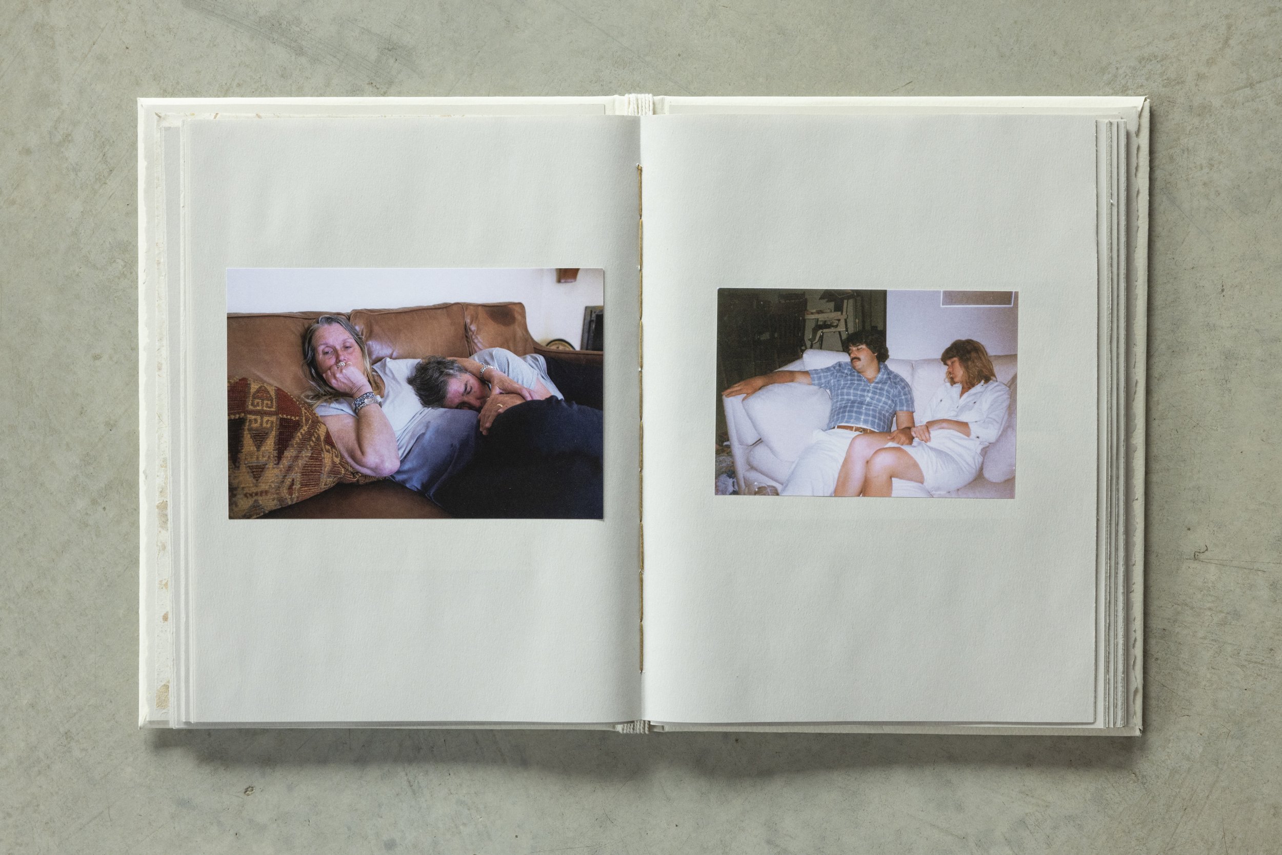 Open photo album displaying two photographs of people on a beige couch in a living room.