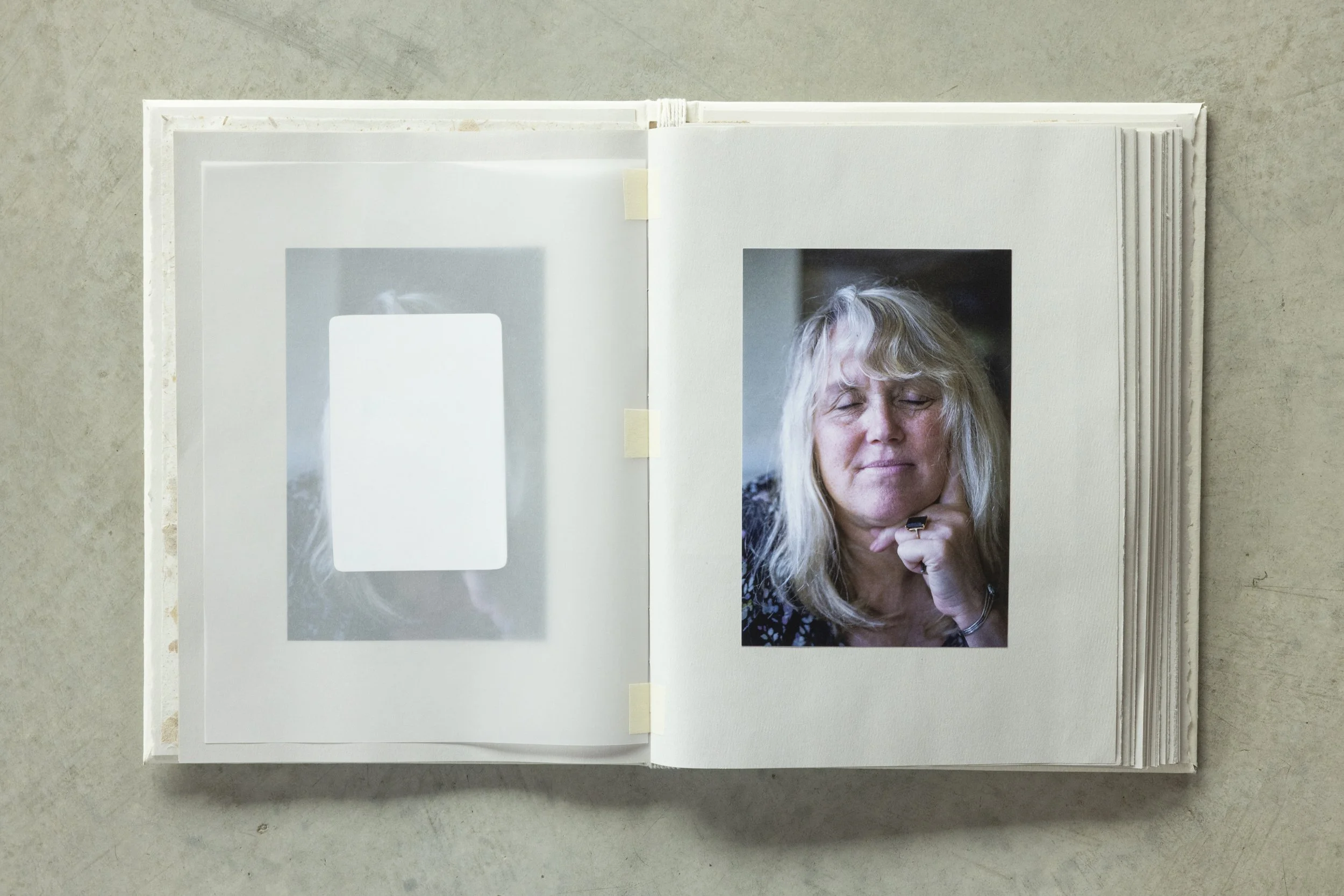 Photo album open to a page featuring a portrait of a woman with blonde hair and eyes closed, resting her chin on her hand, with a finger ring visible.