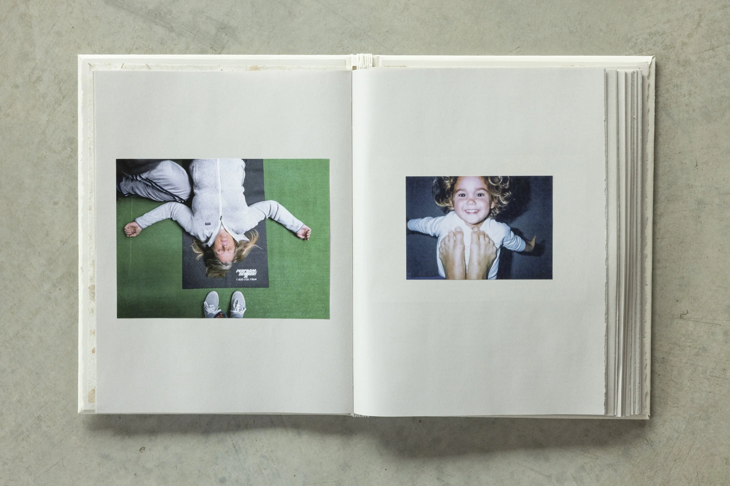 Open photo album with two pages showing photos of children. The left page features a girl lying on a green exercise mat, wearing a gray hoodie and blue athletic pants, with feet in sneakers visible at the bottom. The right page displays a smiling gir