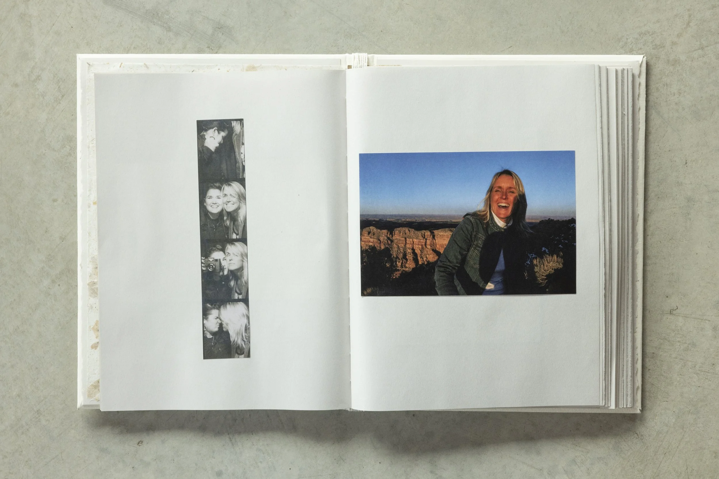 An open photo album showing a row of black and white portraits on the left page and a large color photo of a woman smiling in front of a canyon landscape on the right page.