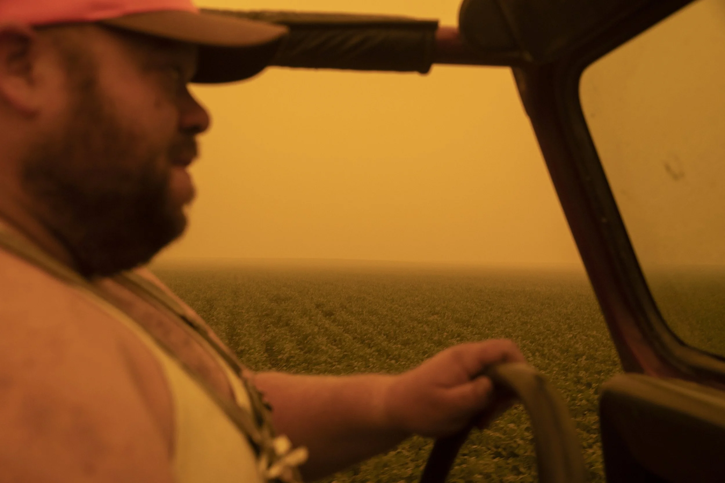A person inside a truck with a yellow-orange sky and open field in the background during wildfires in Oregon.
