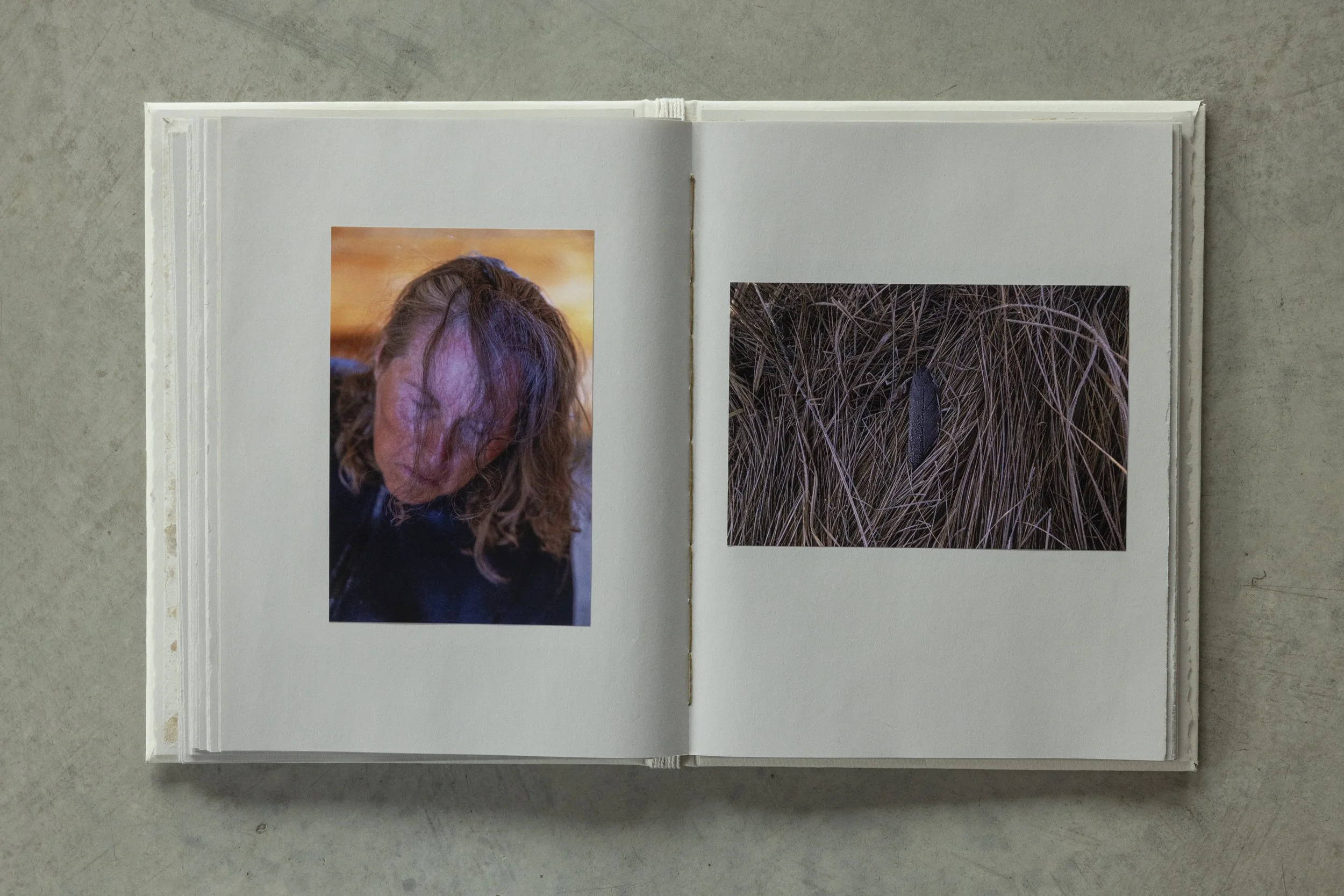 Open photo album with two photos on a plain surface.