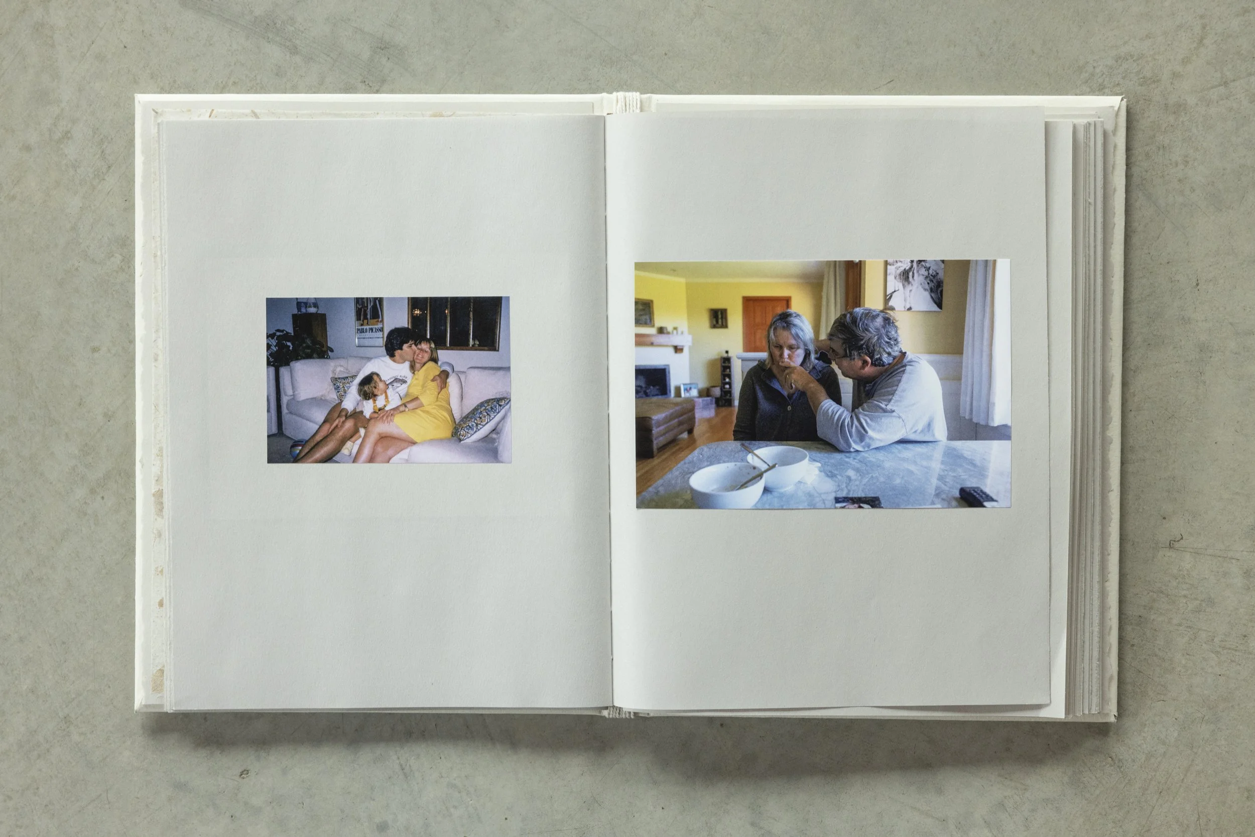 Open photo album showing two pages of photographs on a light gray surface.