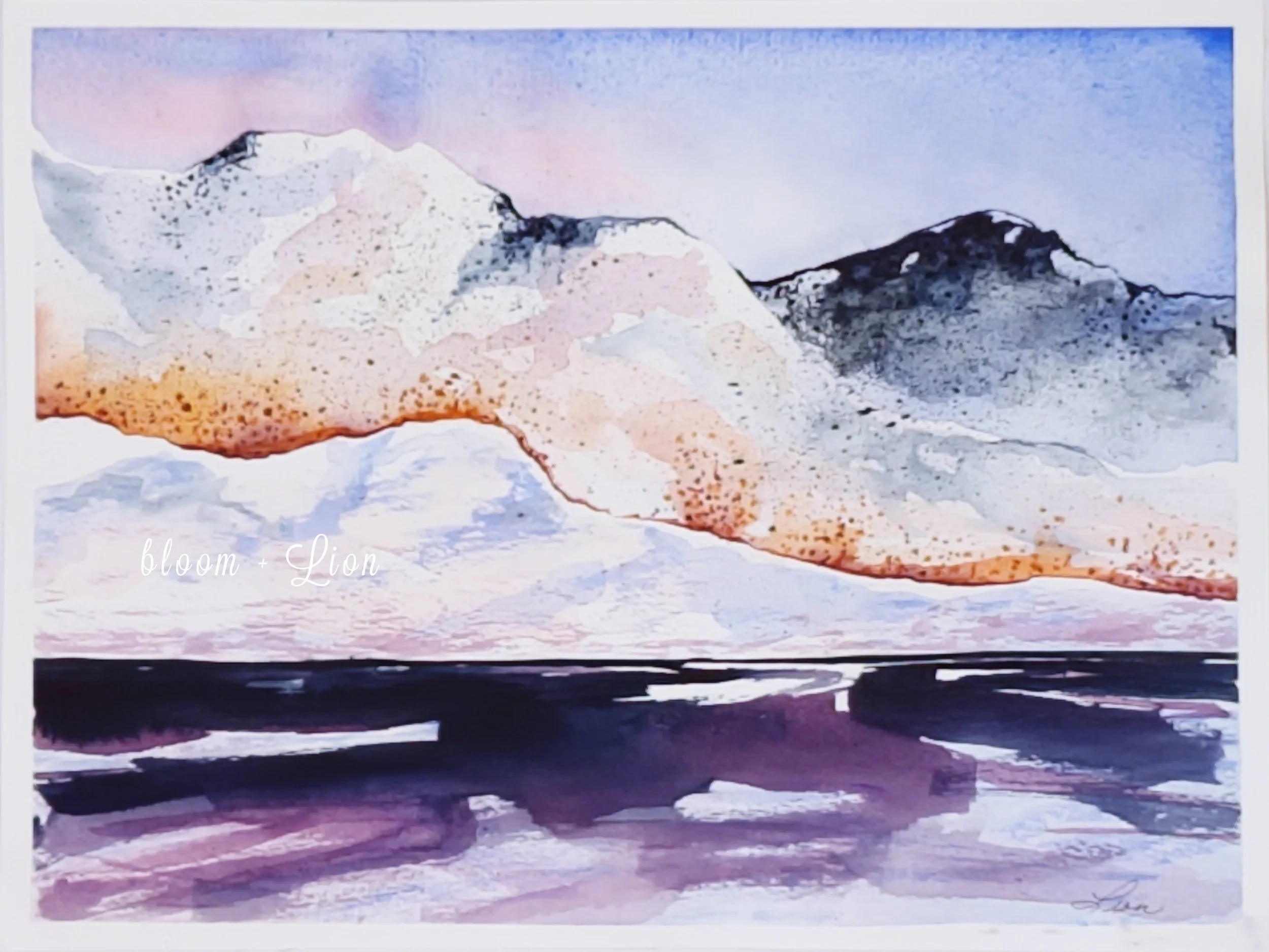 Towering snow covered mountains against a blue and pink sky. Water in the foreground is dark blue and dark purple.