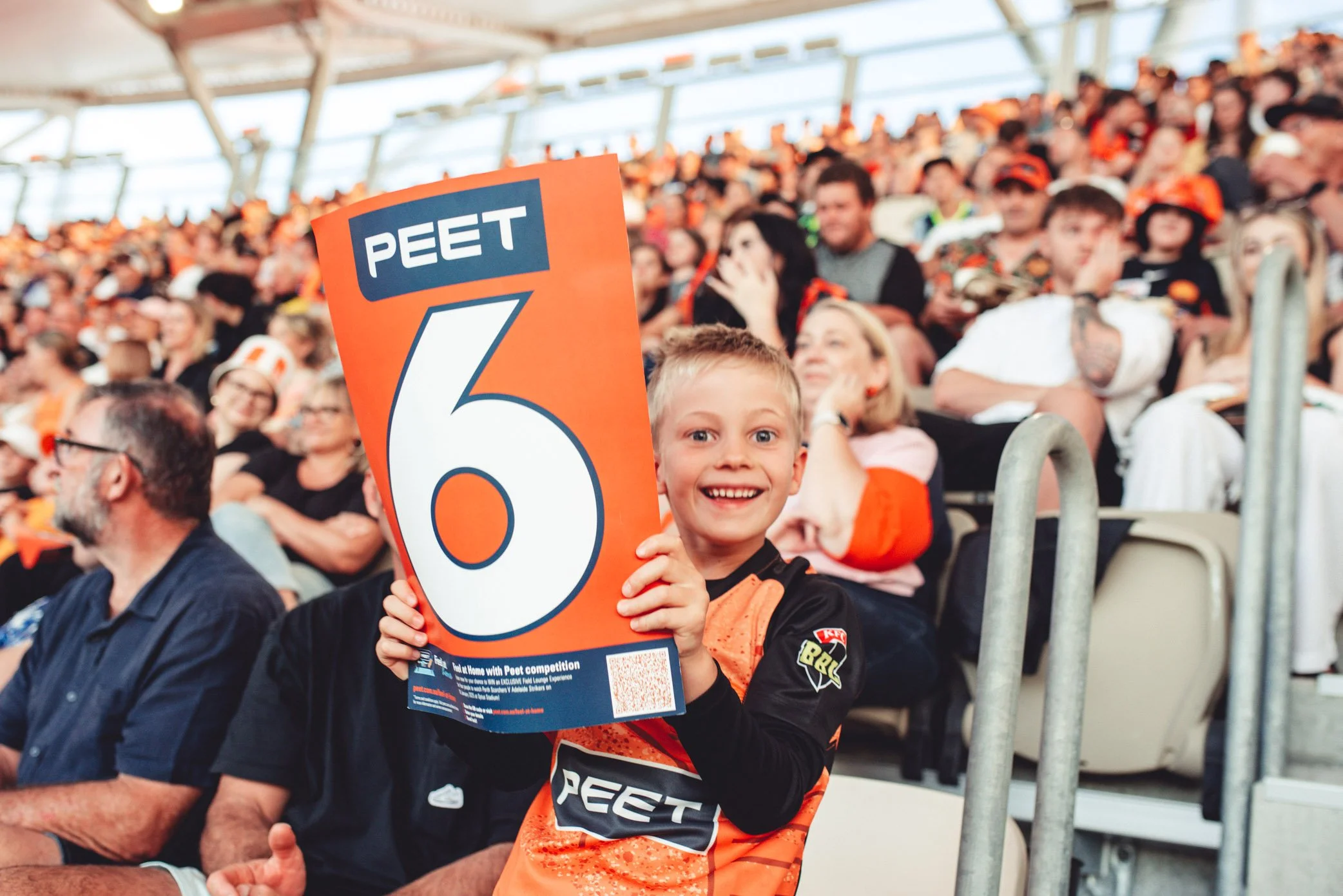 Young fan holding a Peet cheer card at a Perth Scorchers match