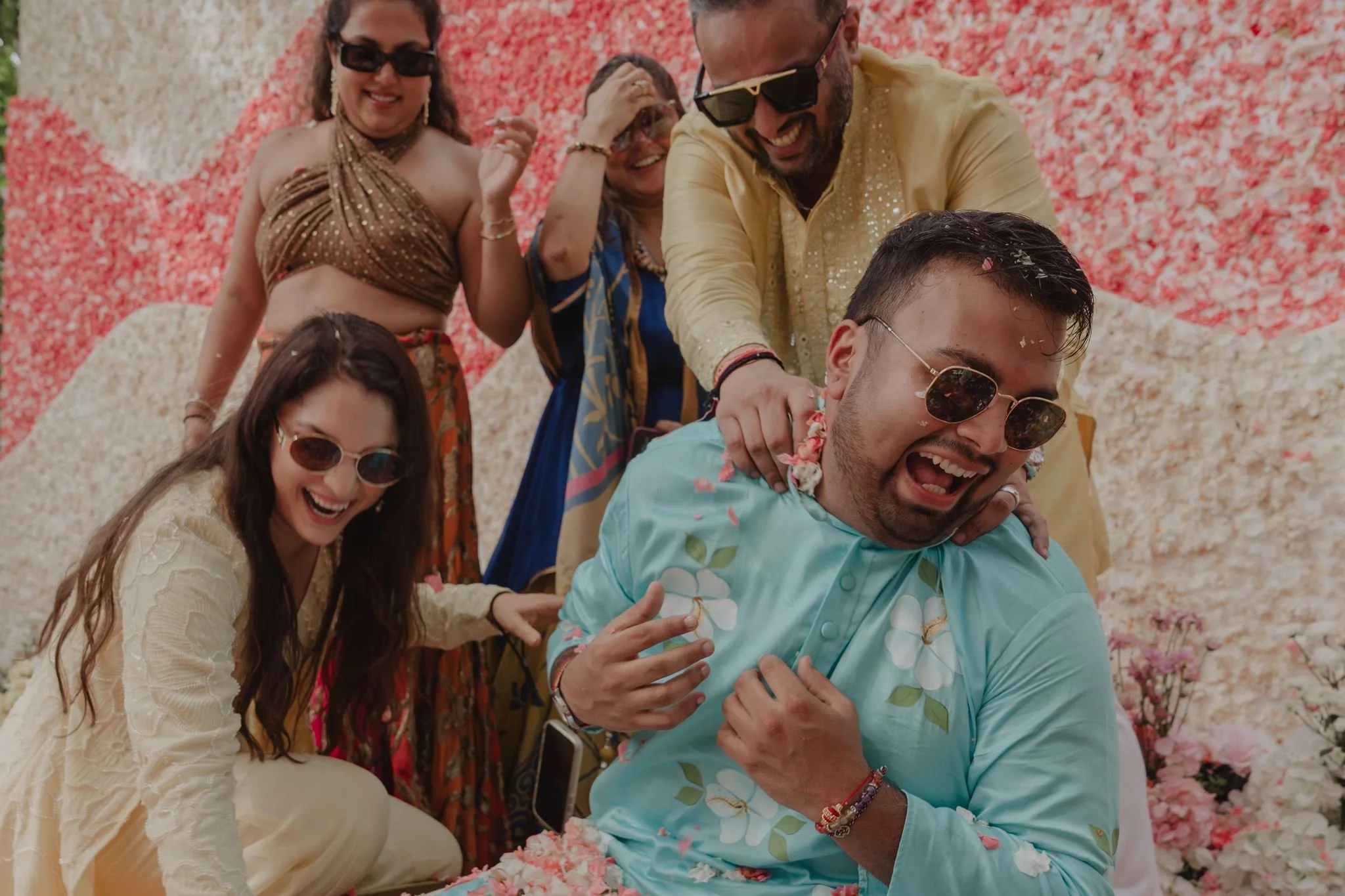 Groom laughing with family during a colourful Flower Haldi celebration