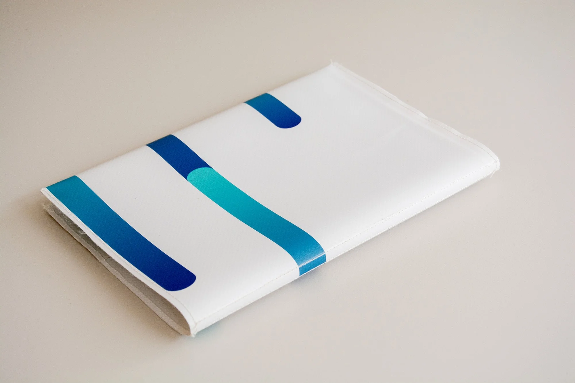 Libreta con grapas con diseño de abstracto y colores divertidos y espacio para añadir logotipo. Sobre fondo neutro.