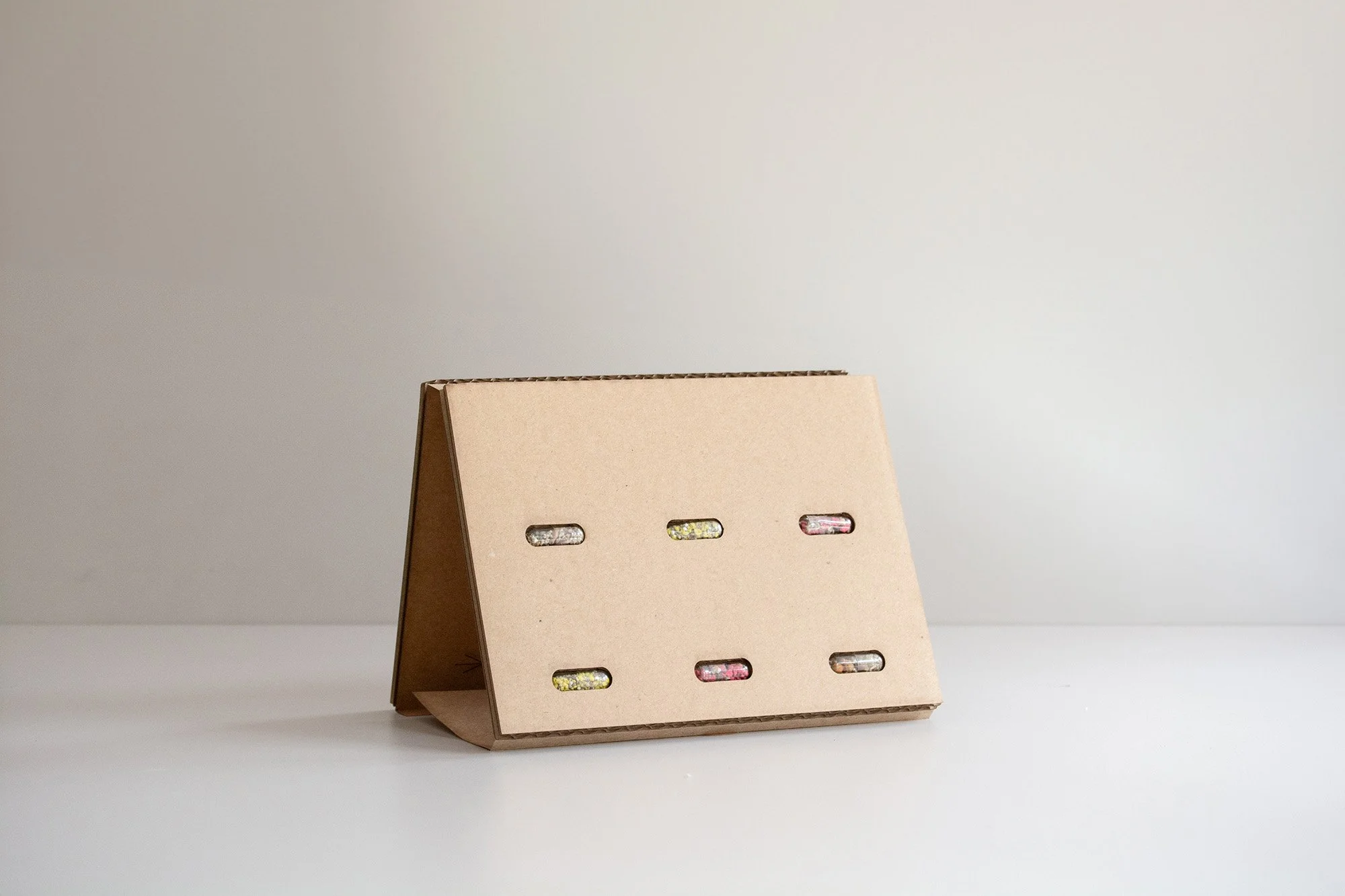 Caja rectangular hecha de papel de algas con espacio para personalizar el logo y diseños azul y gris sobre fondo blanco en una mesa neutra.