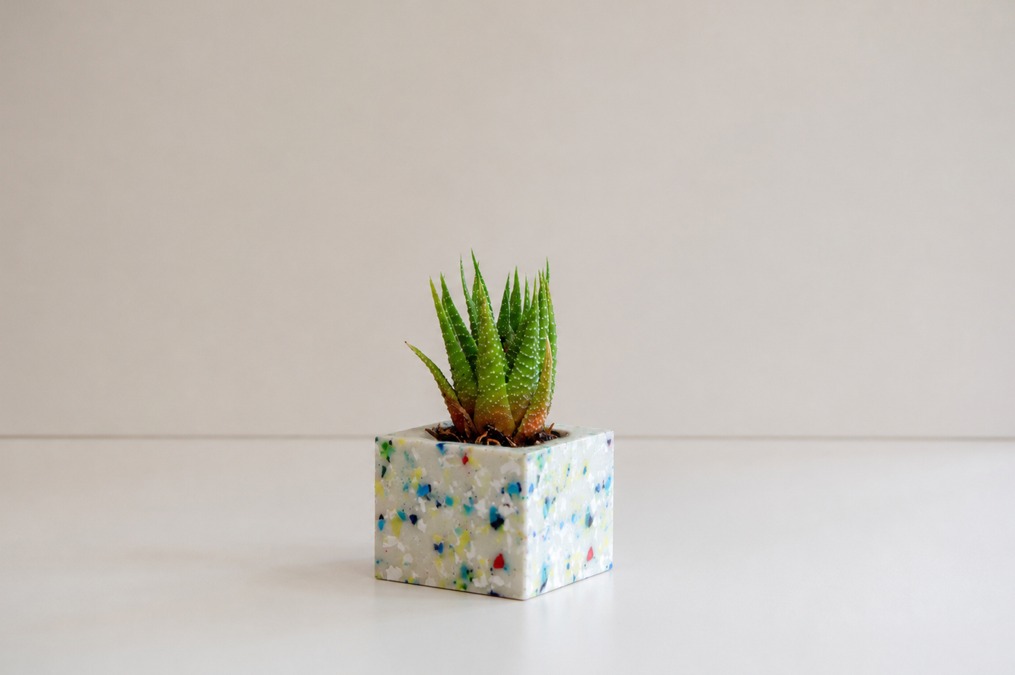 Una caja decorada con formas abstractas en tonos azules y beige, ubicada en un fondo neutro.