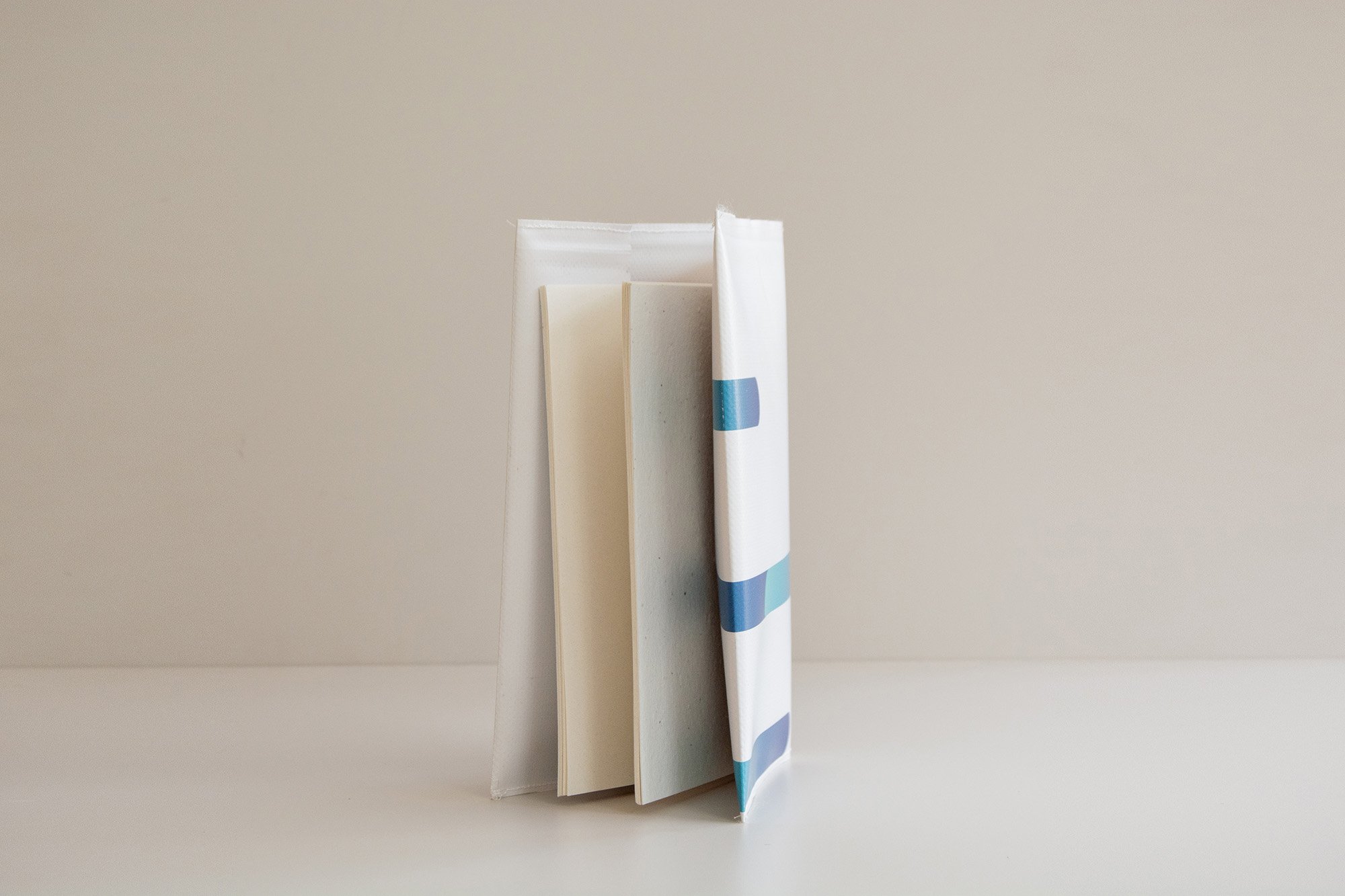 Libreta con grapas con diseño de abstracto y colores divertidos y espacio para añadir logotipo. Sobre fondo neutro.
