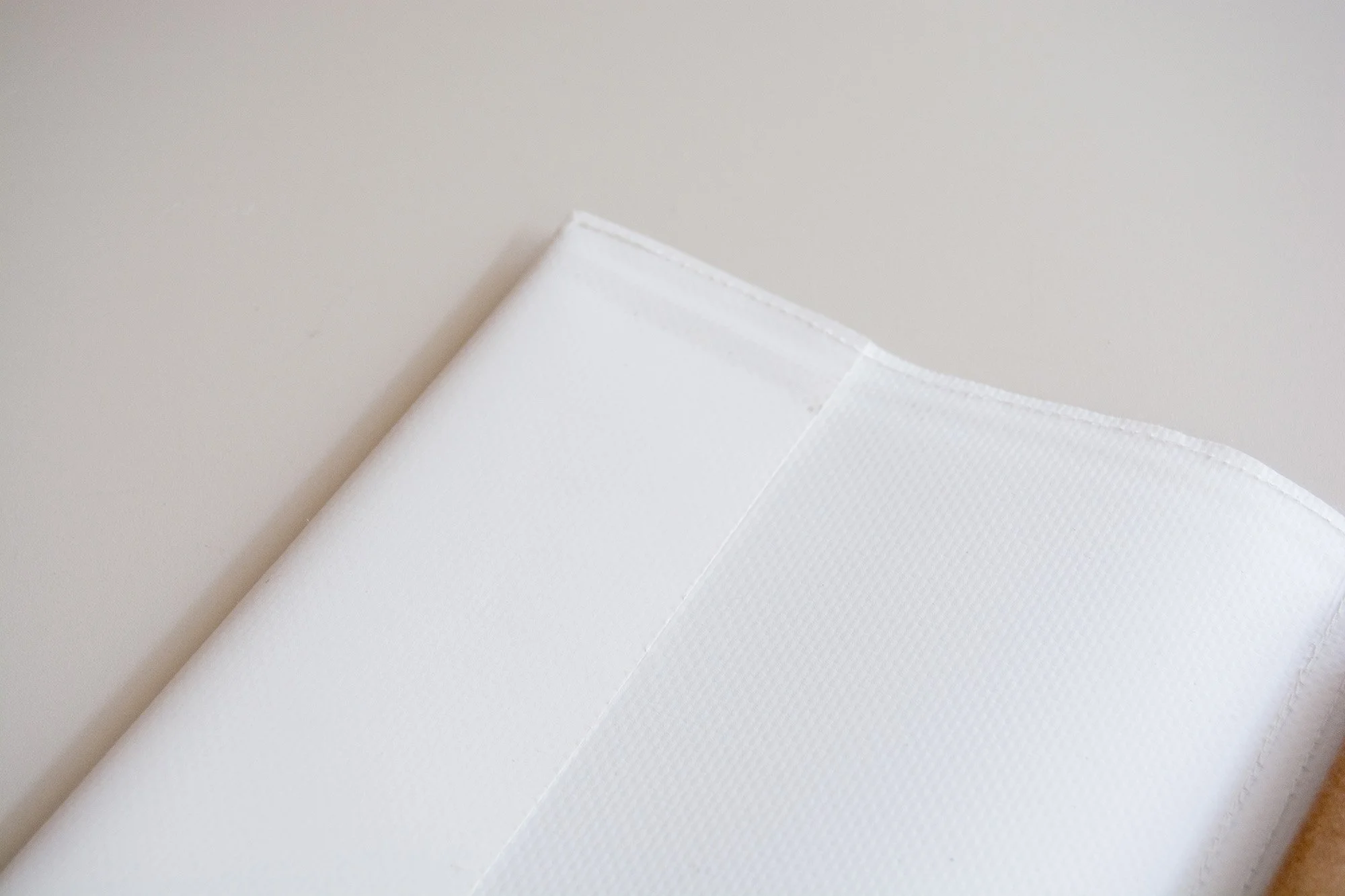 Mano pasando páginas a libreta con grapas con diseño de abstracto y colores divertidos y espacio para añadir logotipo. Sobre fondo neutro.
