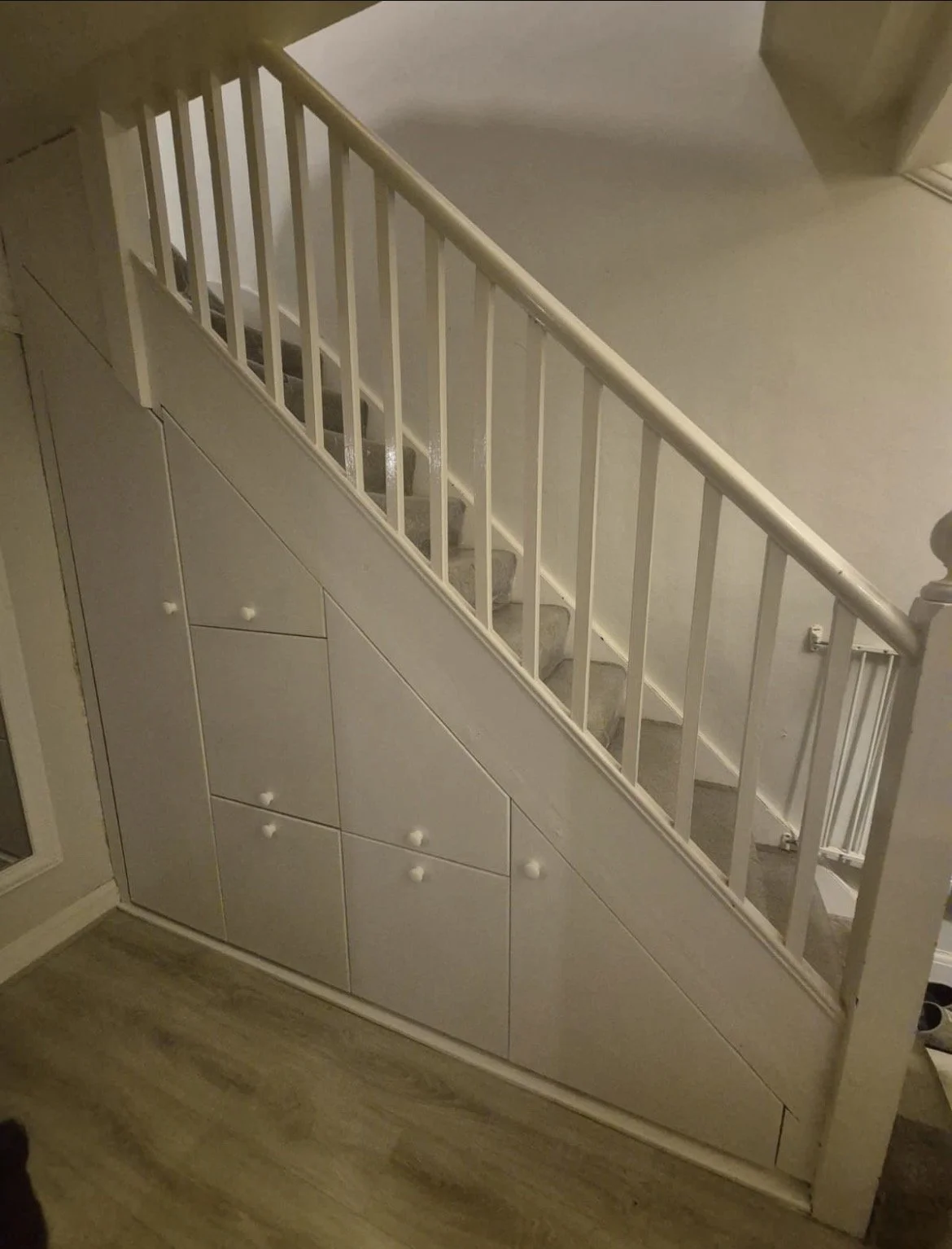 A staircase with a white railing and a built-in storage cabinet underneath.
