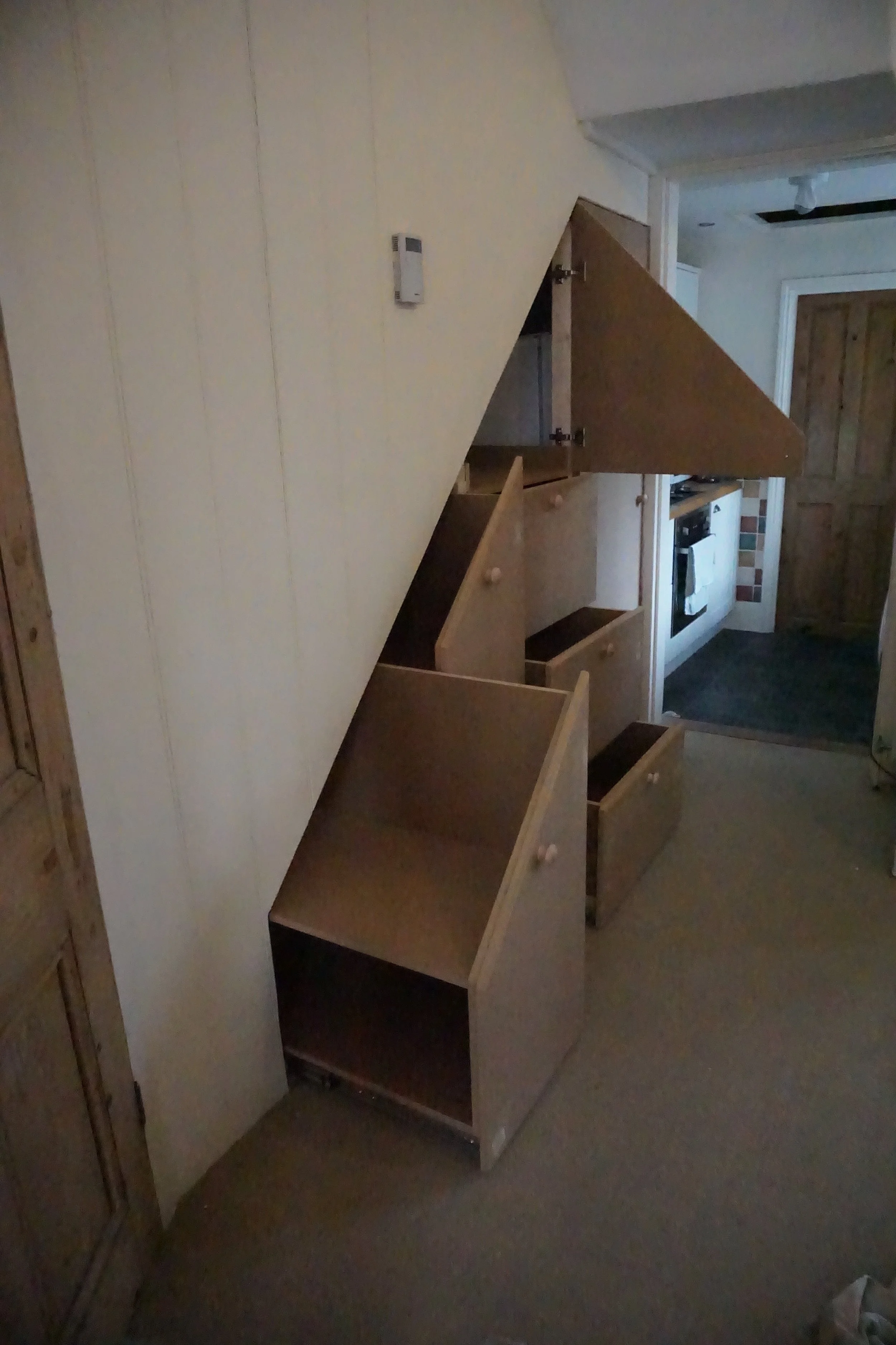 Unfinished wooden cabinetry with open drawers in a home kitchen.