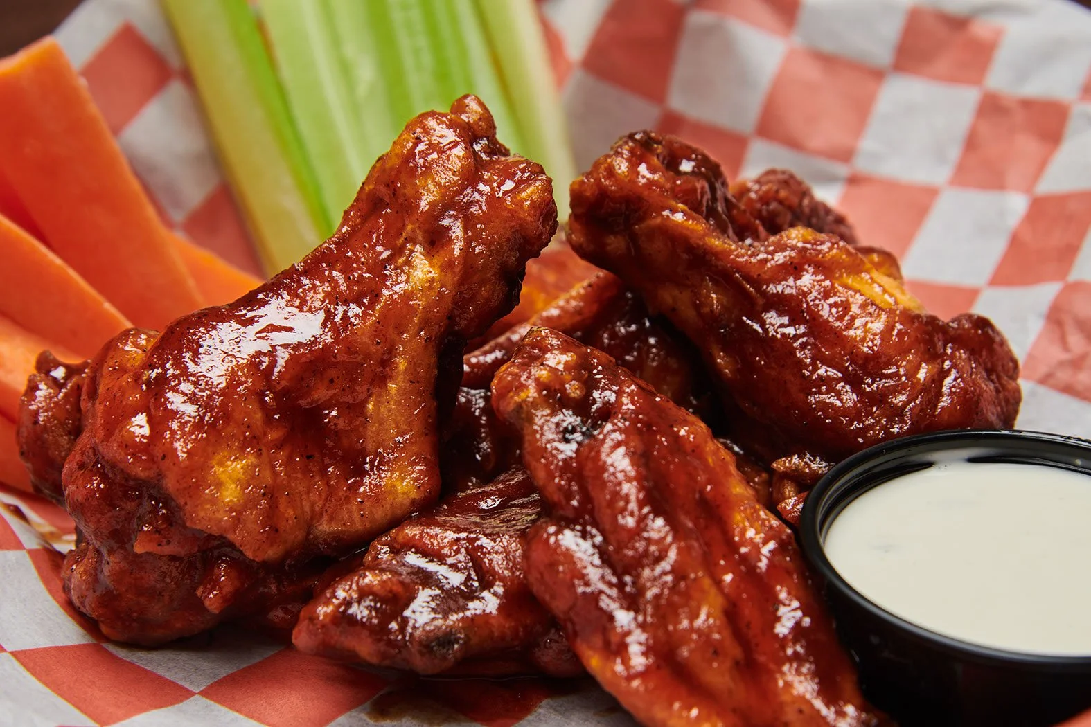 Close-up of buffalo chicken wings with a side of celery, carrots, and ranch dressing.