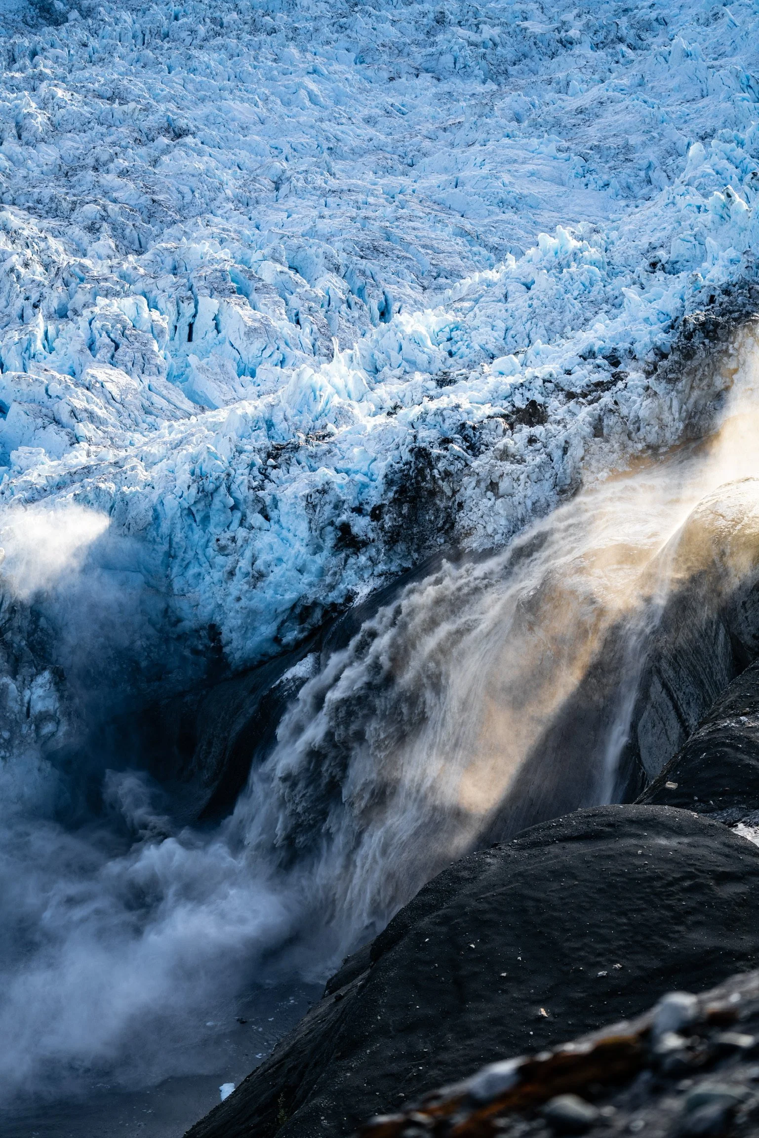 Frozen glacier with flowing water and icy blue ice formations.