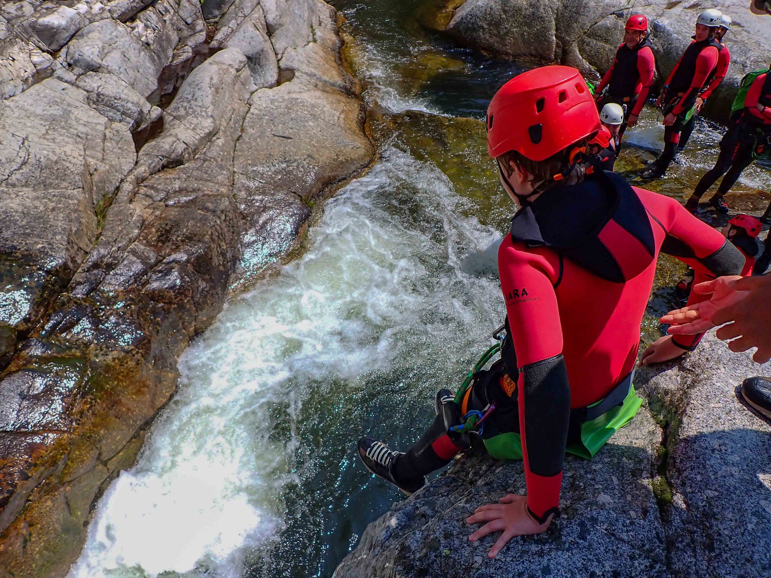 Groupe de personnes en vêtements de sécurité, y compris casques, préparant à faire du rafting dans une rivière rocheuse.