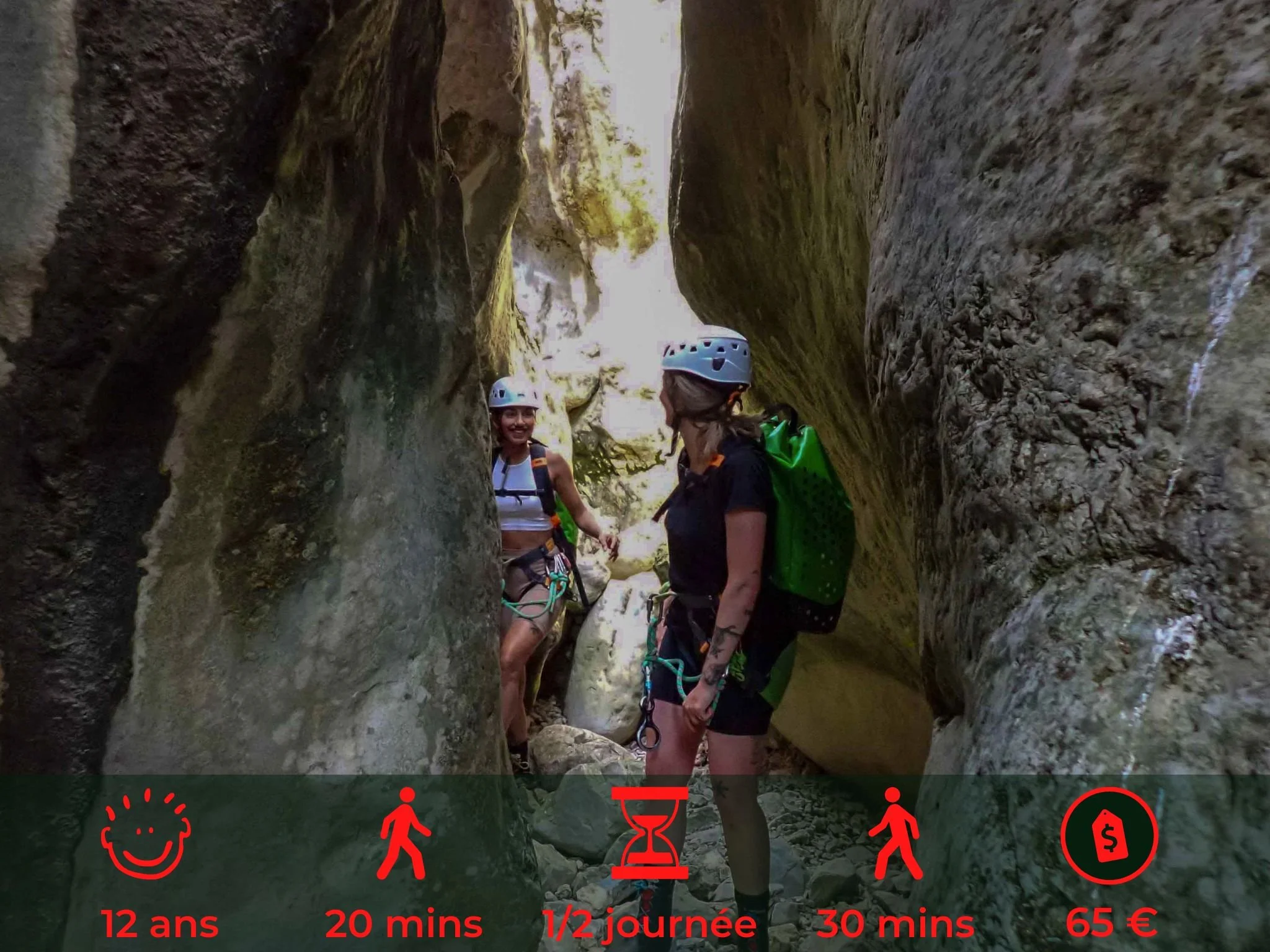 Deux jeunes femmes portent des casques et des chapeaux de randonnée à travers une gorge rocheuse, elles semblent profiter d'une activité d'escalade ou de canyoning.