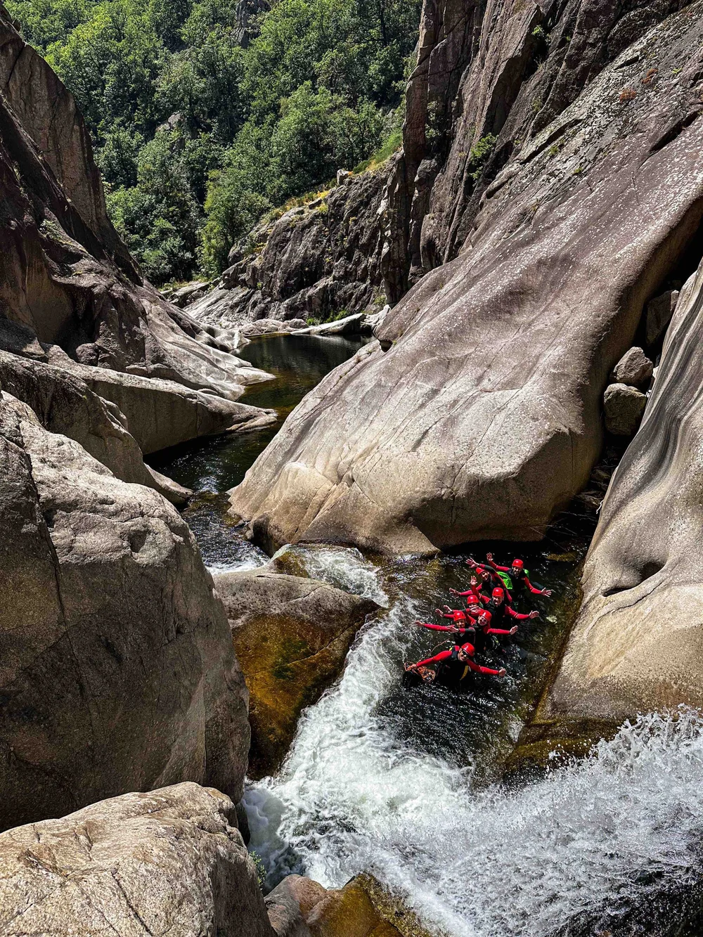 Équipe descendant un toboggan naturel dans les gorges