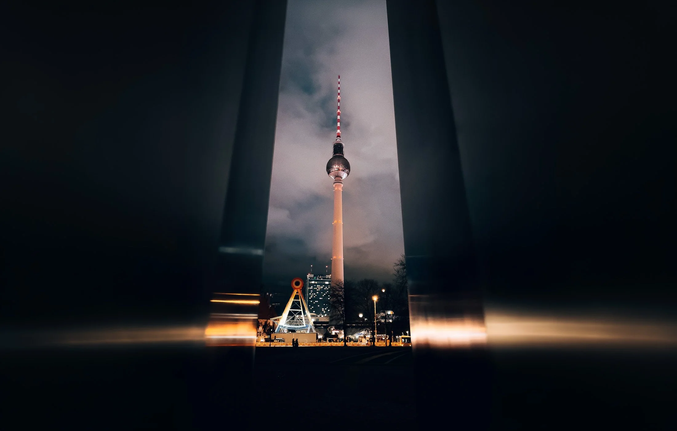 City image from Berlin, photographed by BKMEDIA, Badi Khwies. The image shows the Berlin TV Tower at night, framed by dark architecture and city lights. Visual content for travel photography, place branding and urban storytelling.