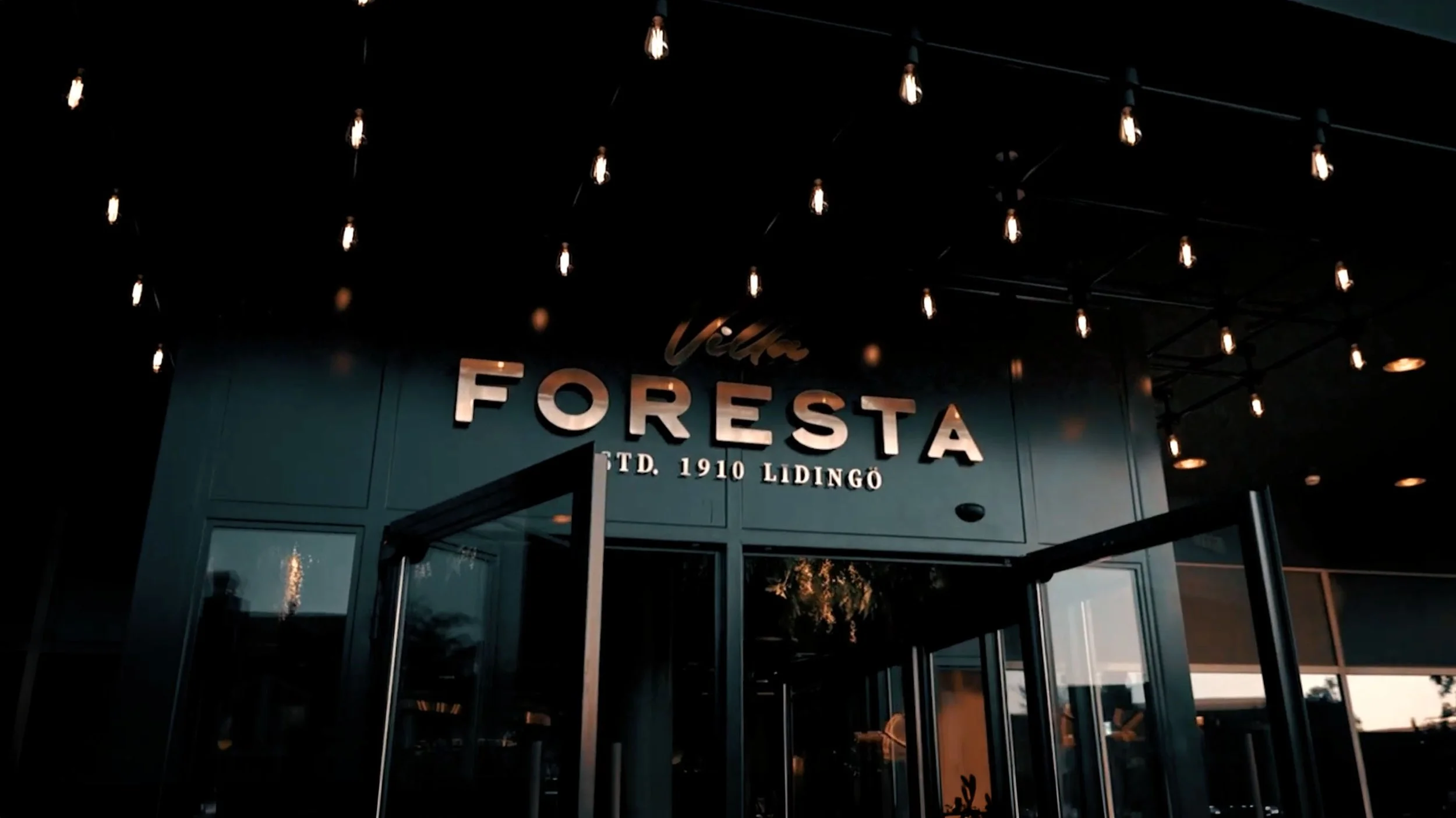 Filmframe från invigningsfilmen för Villa Foresta på Lidingö, producerad av BKMEDIA. Bilden visar entrén med en varm och exklusiv kvällskänsla. BKMEDIA skapar eventfilm och visuellt innehåll för hotell, mötesplatser och varumärken.
