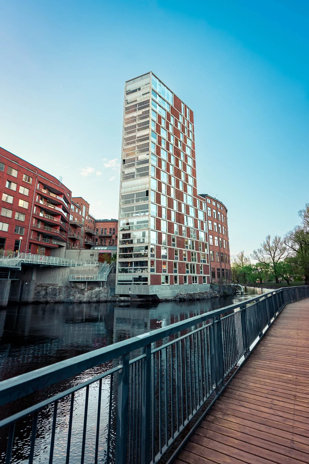 Stadsbild från Norrköping, fotograferad av BKMEDIA Fotograf: Badi Khwies. Bilden visar modern arkitektur vid Motala ström med höga byggnader, gångstråk och vattennära stadsmiljö. Skapad för platsmarknadsföring, destinationer och visuell kommunikation