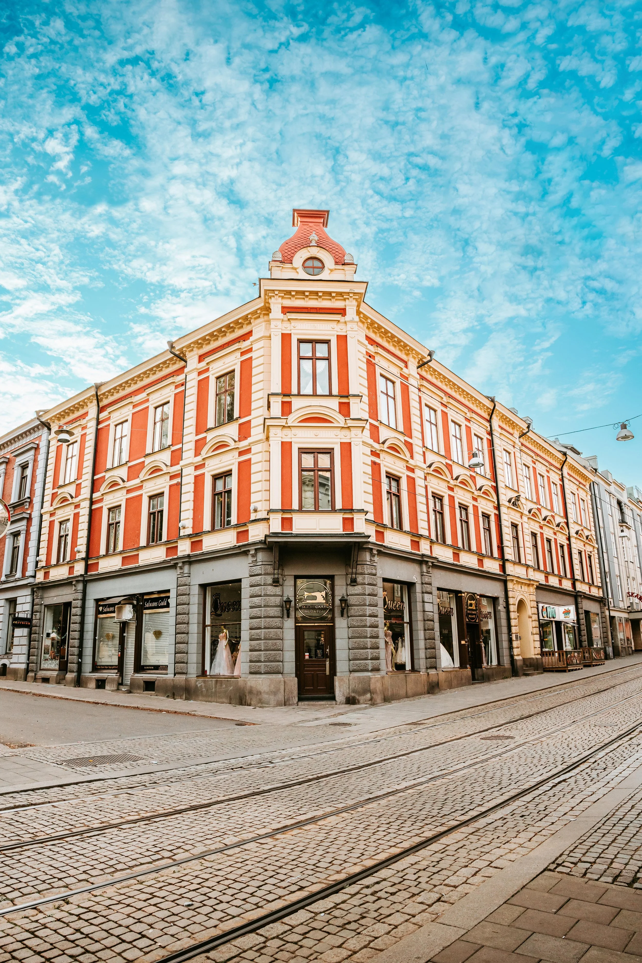 En vacker byggnad i centrum av en stad med gator och spårvagnsspår framme.