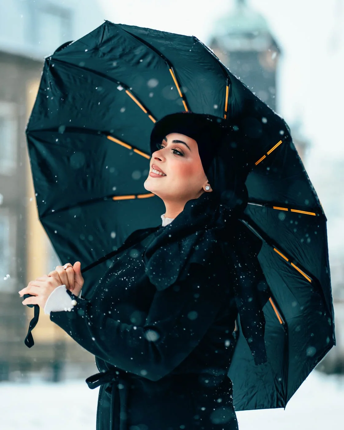 Porträttfoto från Norrköping, fotograferat av BKMEDIA, Badi Khwies. Bilden visar ett elegant modeporträtt med paraply, snöfall och mjukt stadsljus i bakgrunden. Visuellt innehåll för porträtt, kreativa projekt och personlig kommunikation.