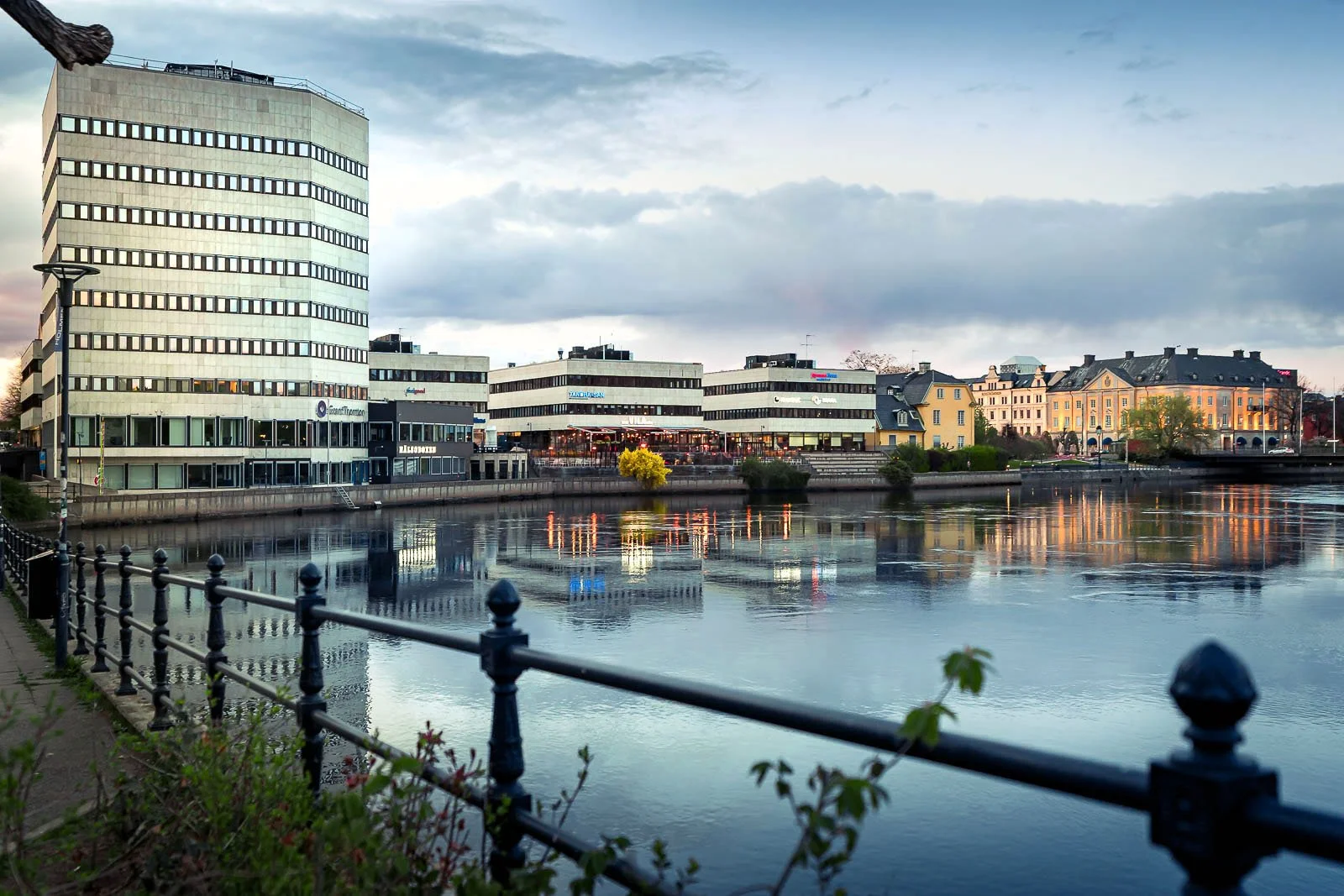 Stadsbild från Norrköping, fotograferad av BKMEDIA, Badi Khwies. Bilden visar Holmenområdet vid Motala ström med stadens byggnader, räcken och speglingar i kvällsljus. Visuellt innehåll för platsmarknadsföring, destinationer och stadsmiljöer.