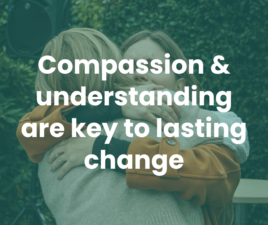 Two people hugging outdoors with blurred greenery in the background, the message text overlays saying 'Compassion & understanding are key to lasting change'.