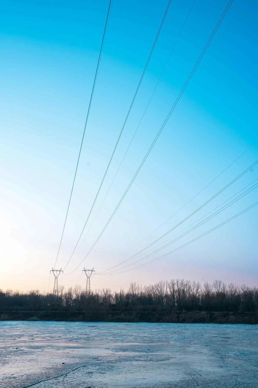 Two transmission lines along the bank of a river.