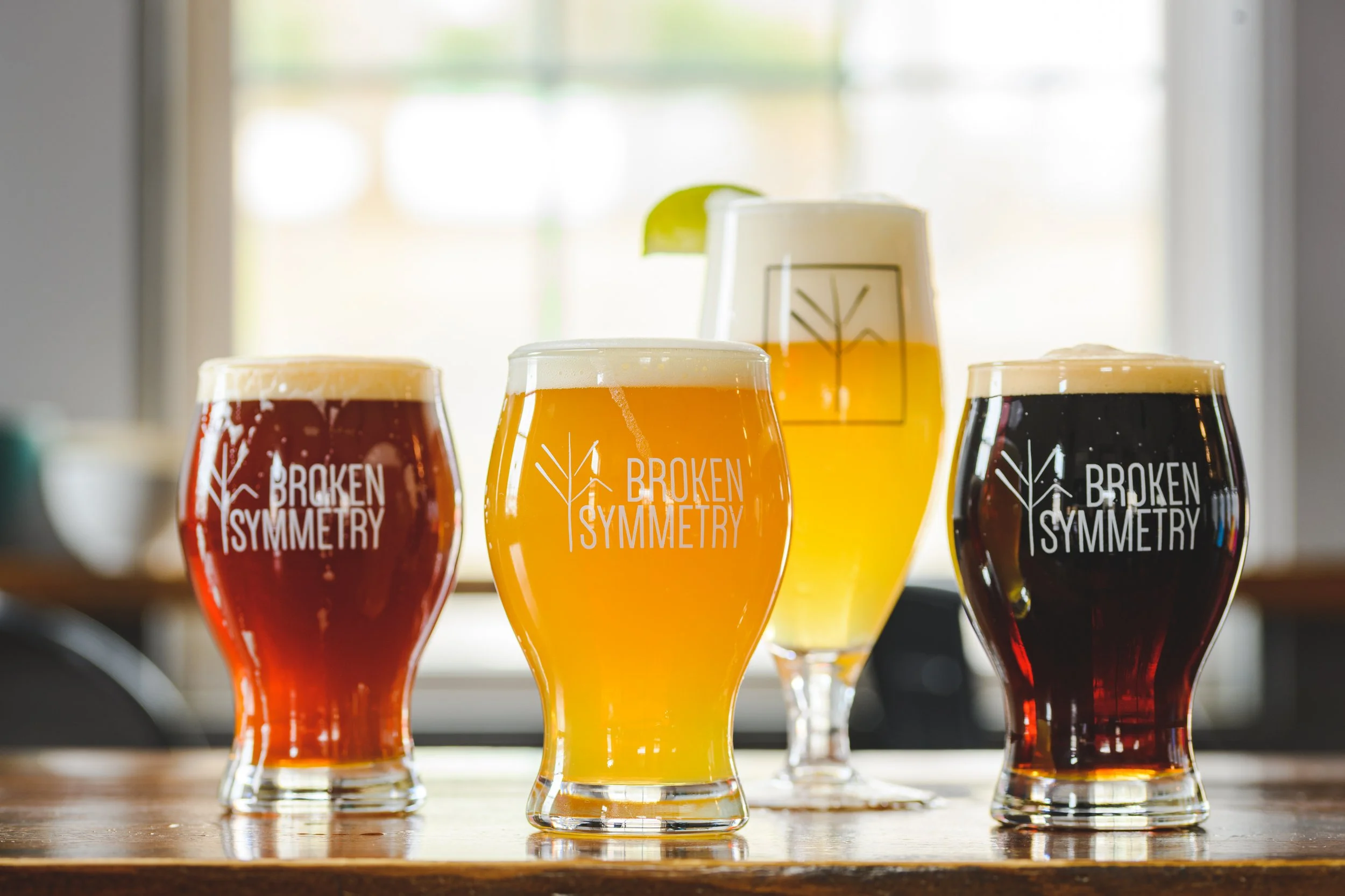 4 different styles of beer in Broken Symmetry branded glassware