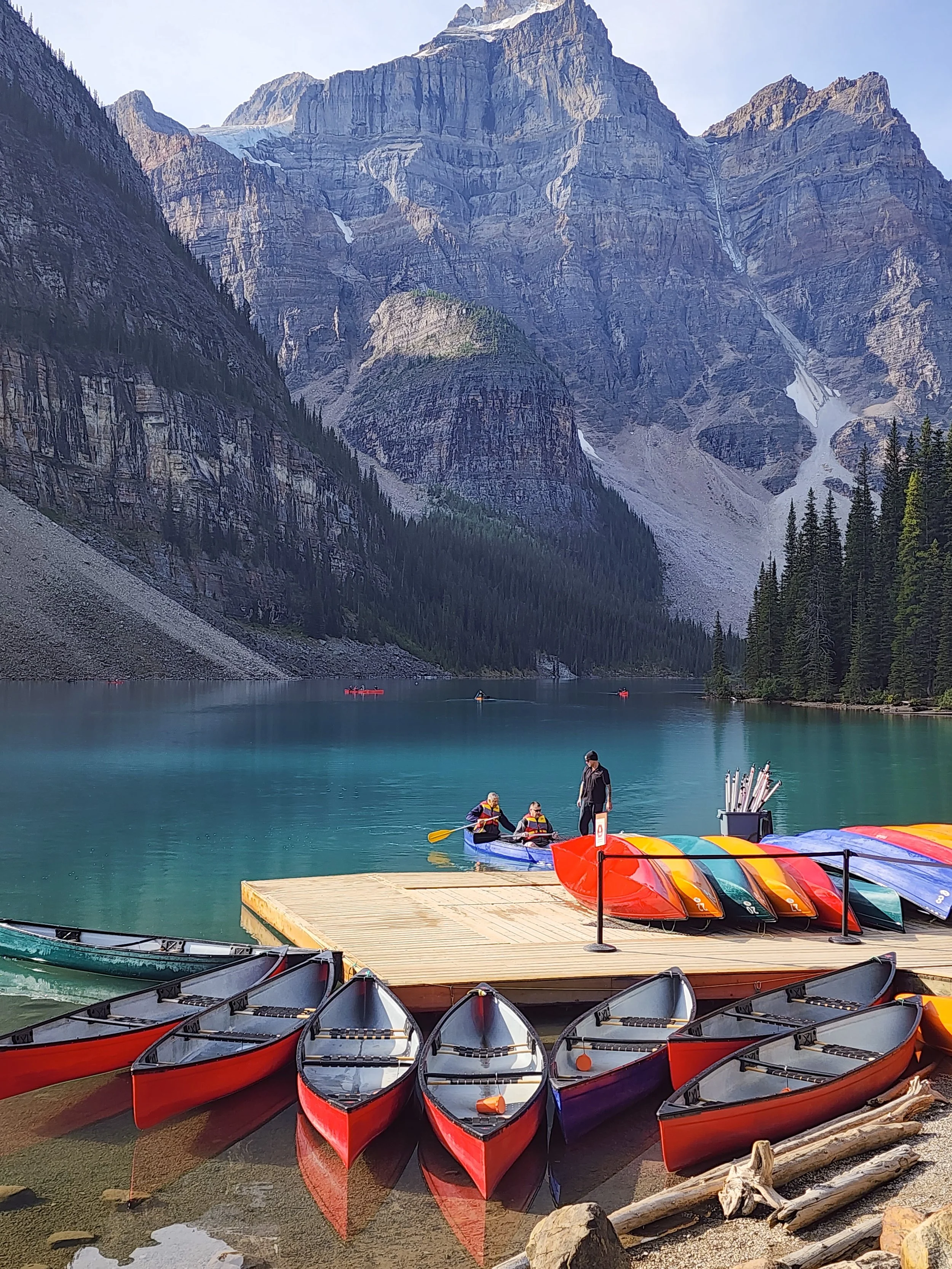 A tandem canoe docking at Lake Louise in the morning with giant mountains in the distance.