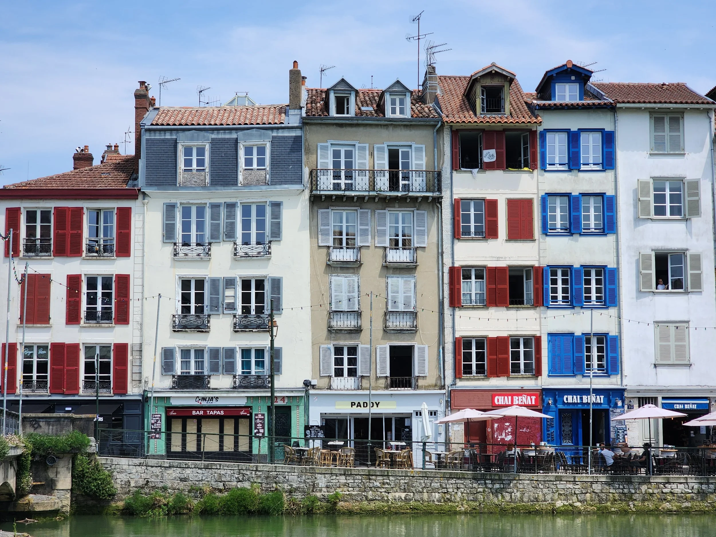 Narrow, tall, colorful, traditional houses in Bayonne, France on a sunny day.