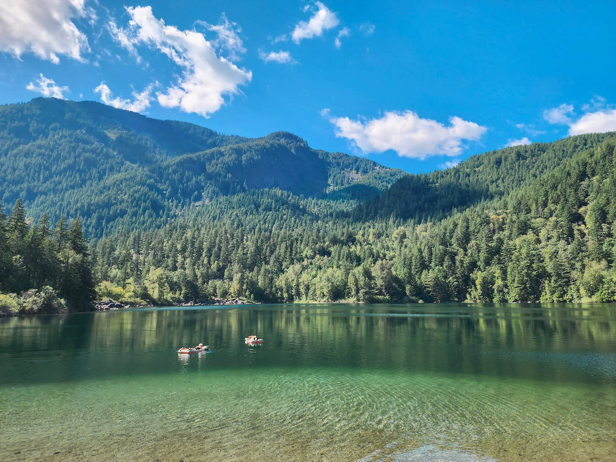 Two people floating at Lake of the Woods on a sunny day in British Columbia.