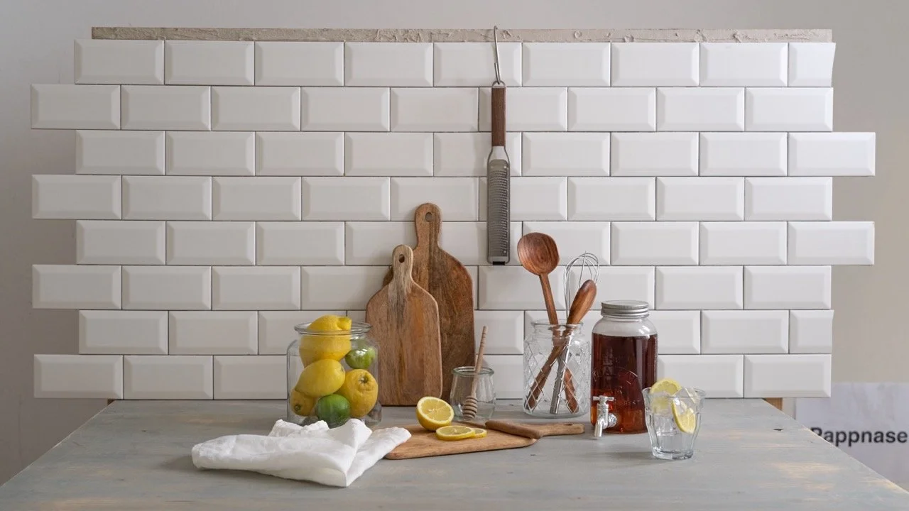 Moderne Küche mit weißen Schränken, Kühlschrank, Waschmaschine, Backofen, Spüle und Küchenutensilien.