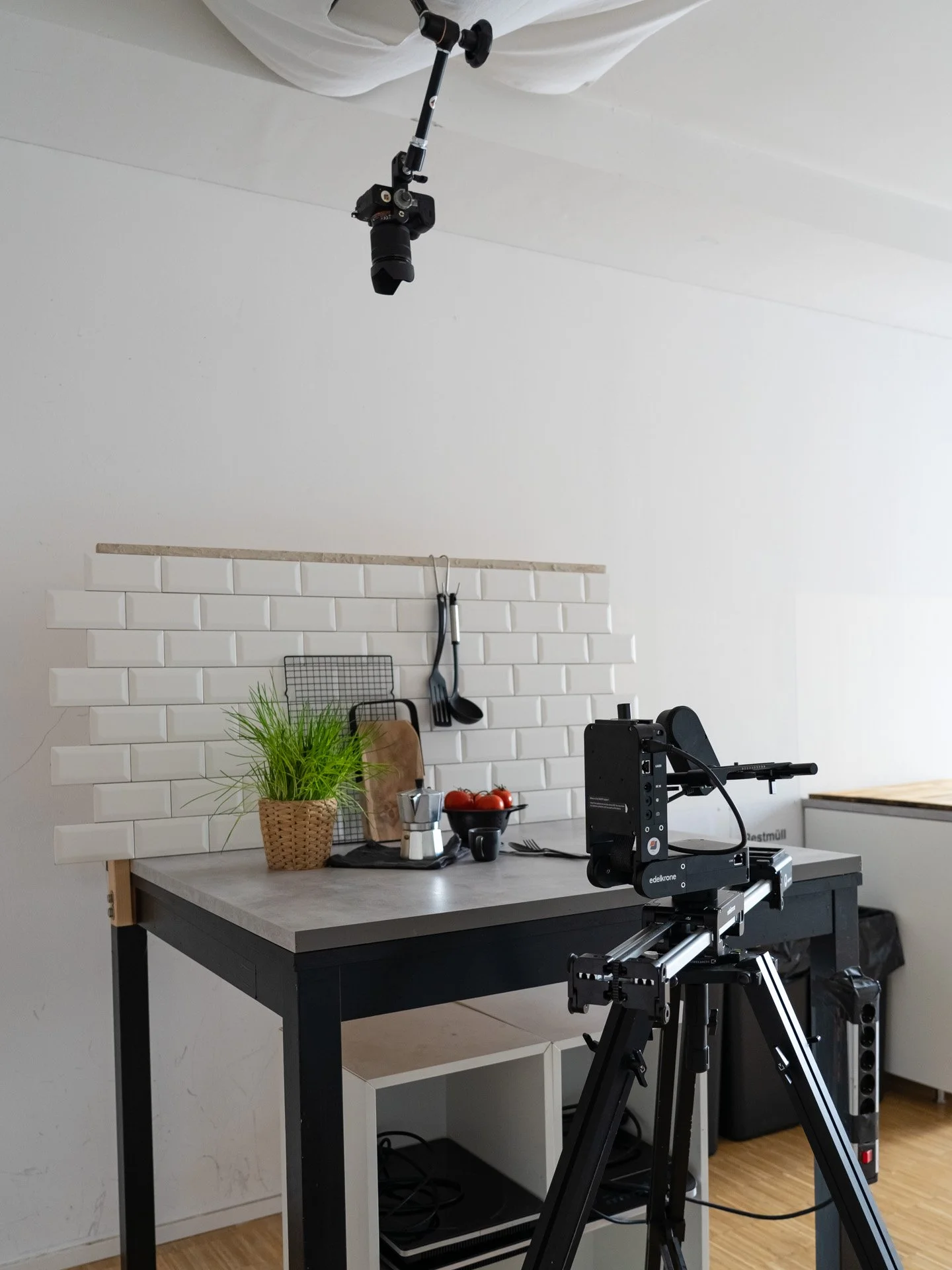 Produktionsküche in Köln mit Kamera und Beleuchtung für Videoaufnahme, weißen Fliesenwand, Küchenutensilien, Topfpflanze auf Tisch