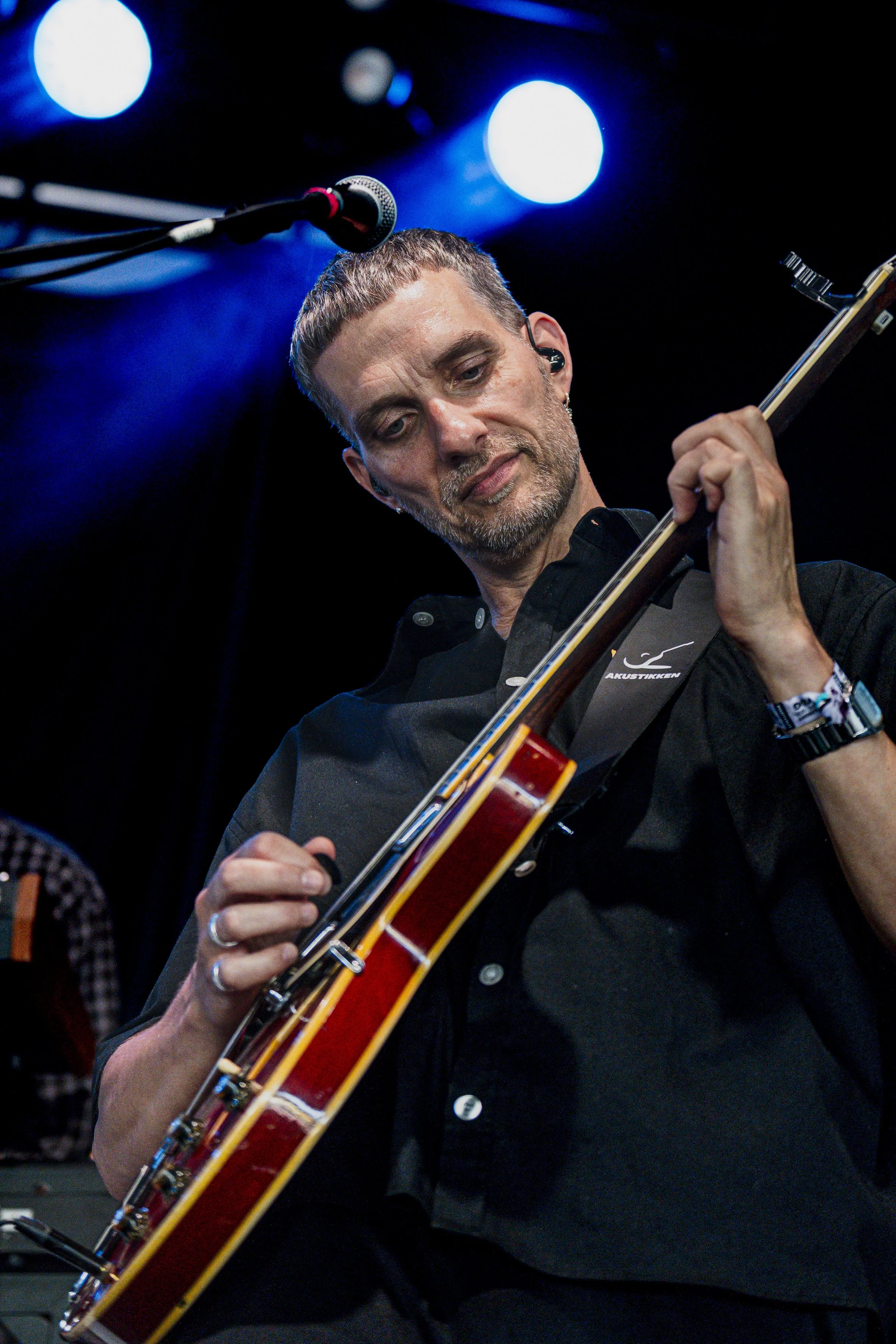 Mand spiller klassisk guitar på scene med blue spotlights.
