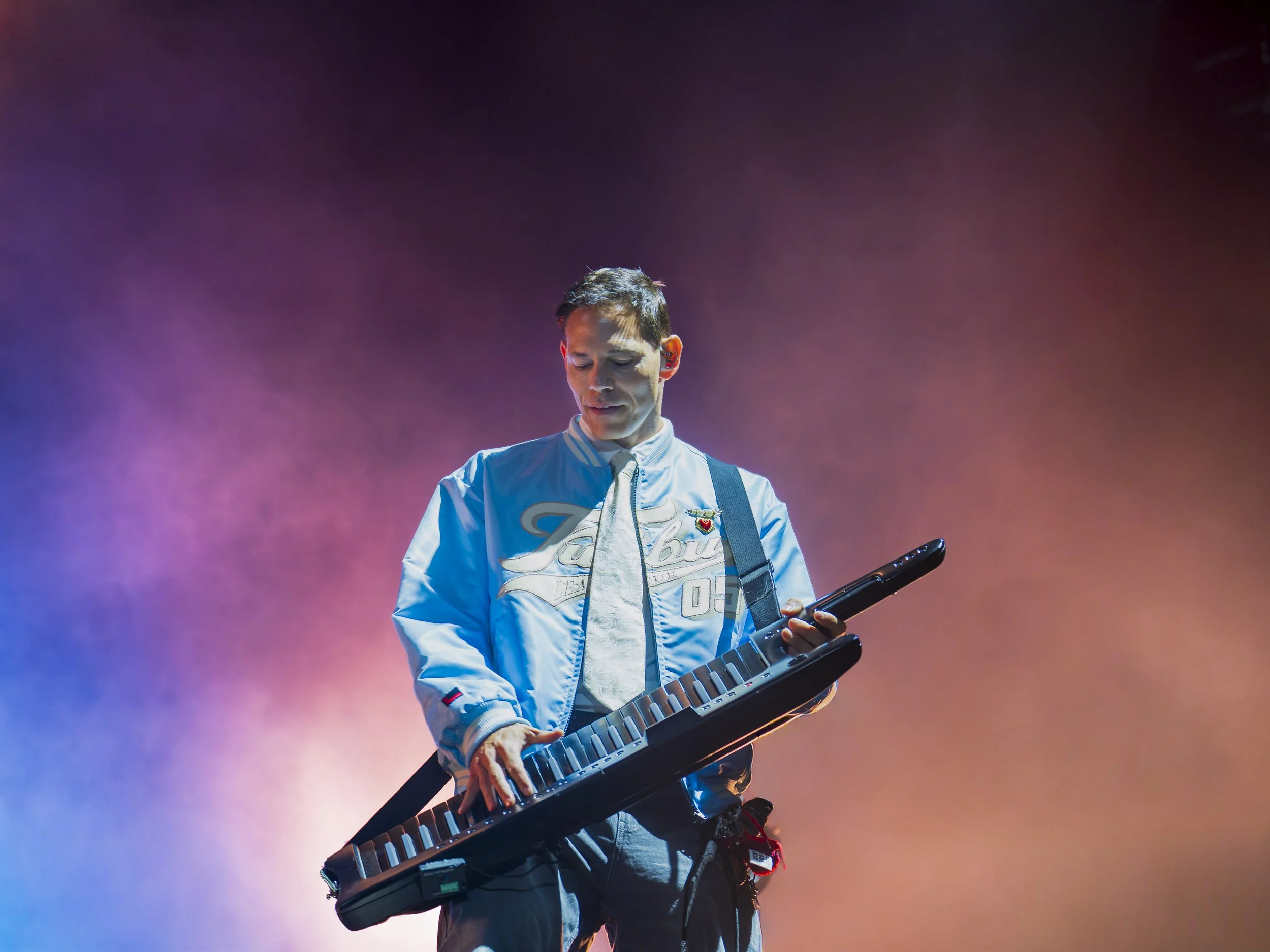 Mand spiller keyboard på scenen med farvet baggrund