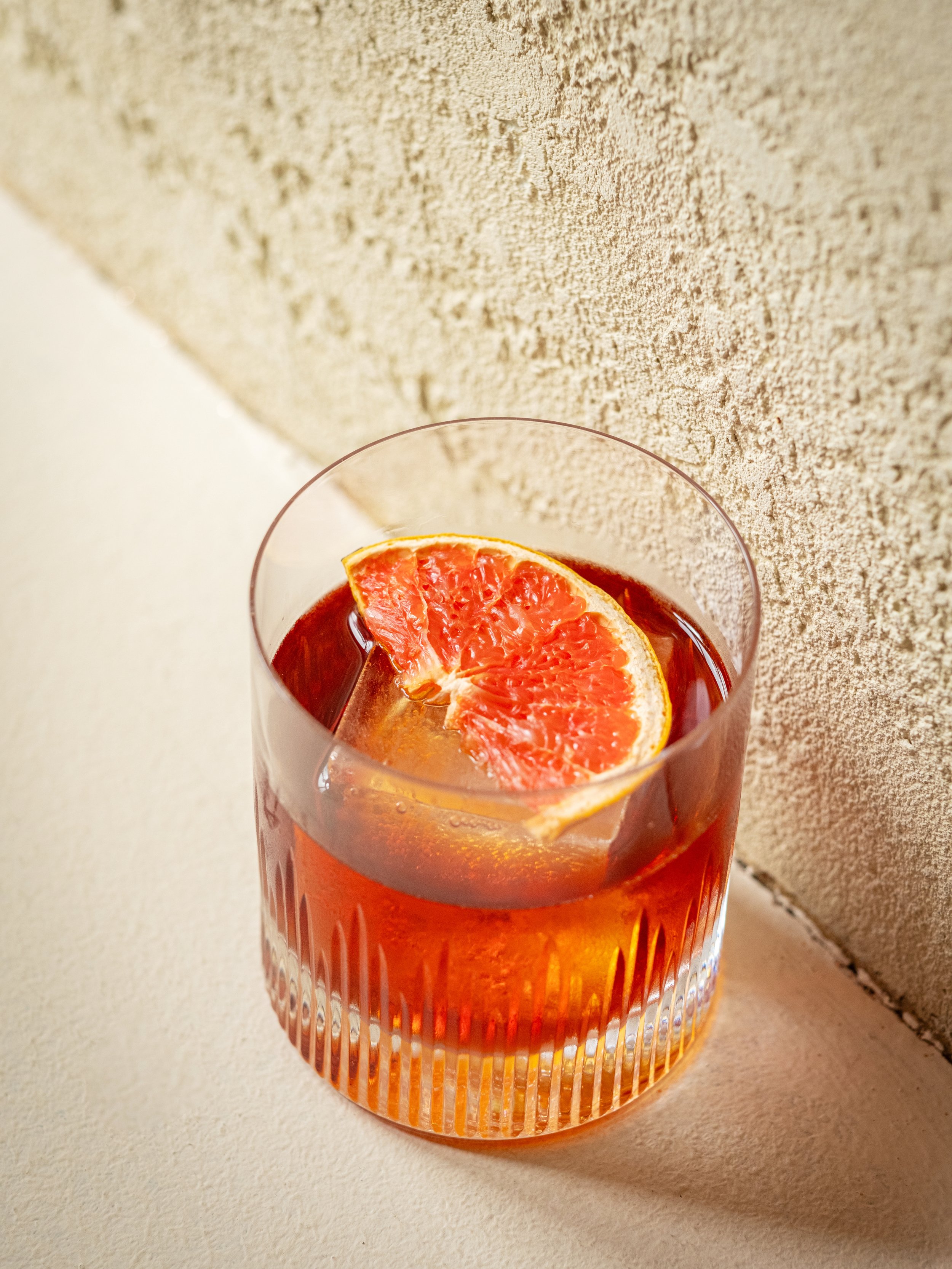 Signature BRICK'S koktejl Negroni, který zachycuje podstatu klasických italských aperitivů, na pozadí našeho elegantního baru, ztělesňuje sofistikované večery v Praze.