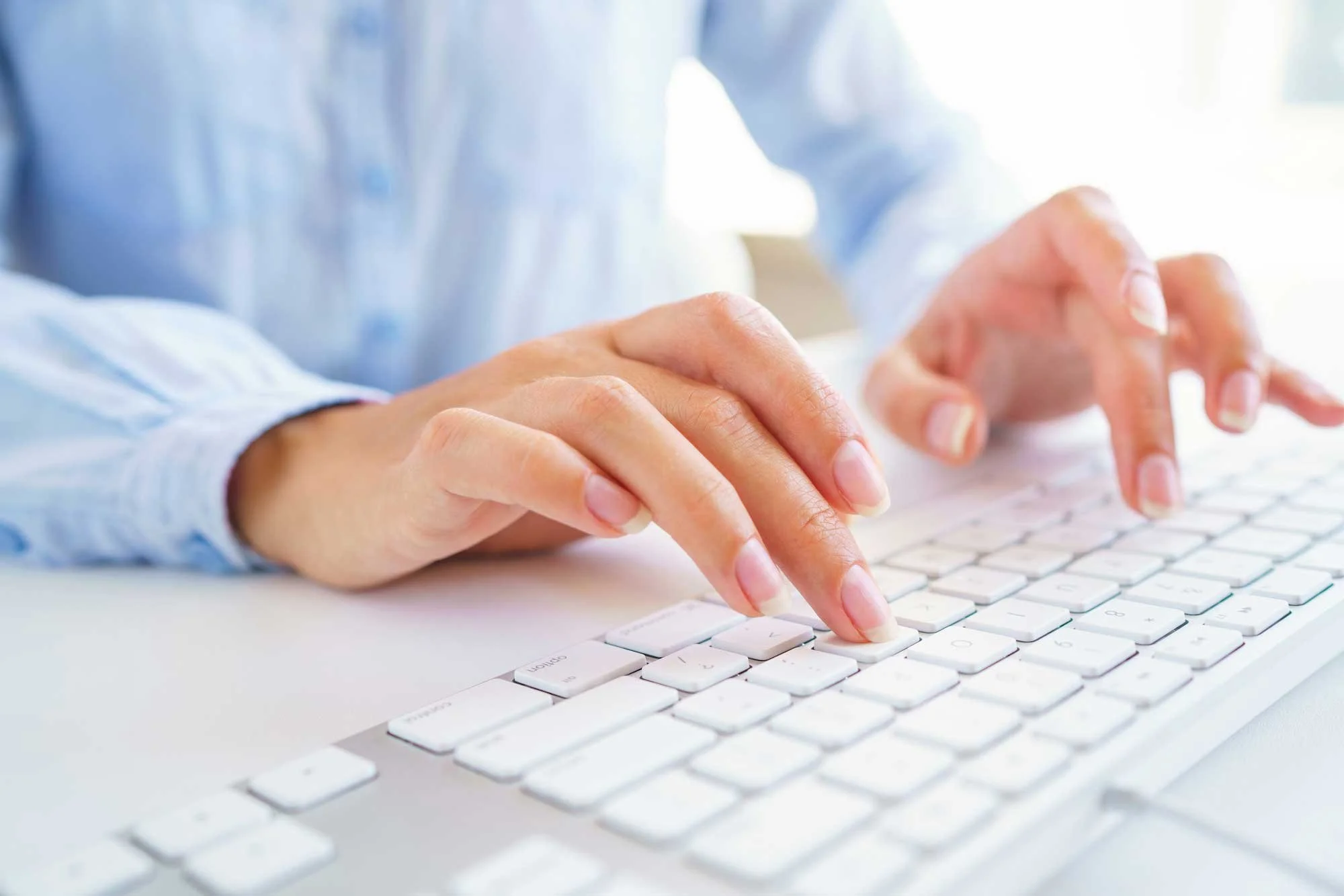 female wearing a blue shirt typing on a keyboard