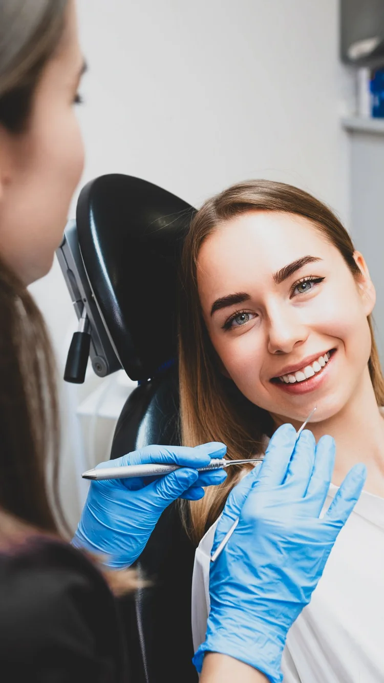 Paciente joven sonriendo feliz y relajada en el sillón dental durante su consulta de periodoncia en Pineda Dental Studio, Recoleta.
