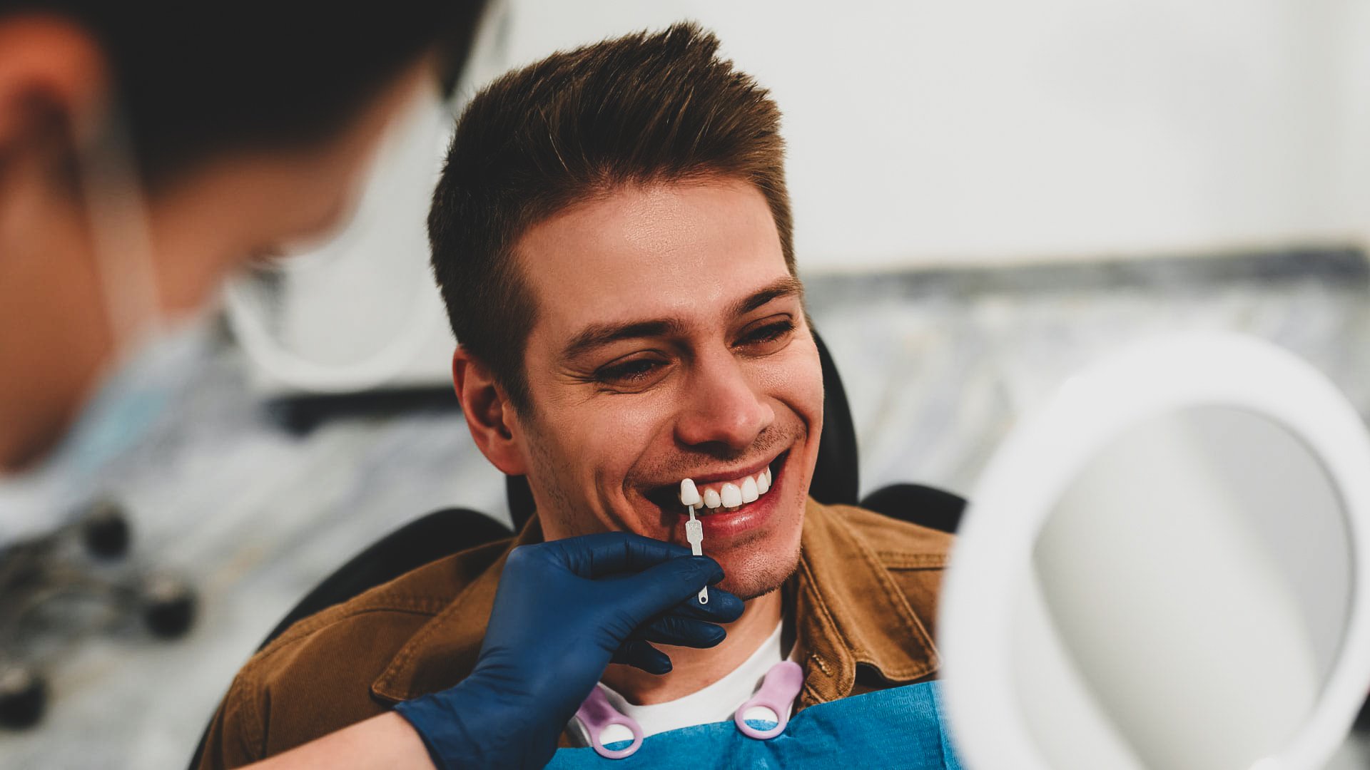 Paciente sonriendo durante una prueba de color dental. Banner promocional para agendar turno por WhatsApp y obtener un plan de diseño de sonrisa a medida en Pineda Dental Studio, Recoleta - CABA.