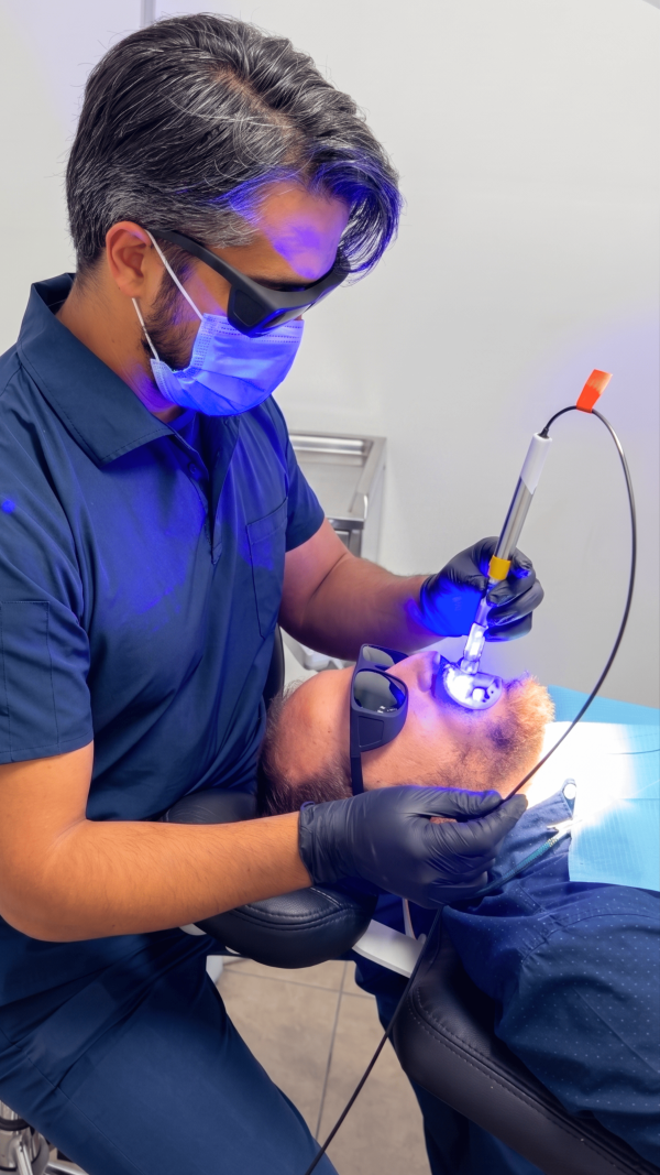 Odontólogo especialista de Pineda Dental Studio realizando un tratamiento mínimamente invasivo con tecnología láser de diodo en paciente, clínica dental en Recoleta