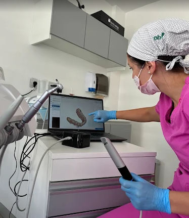 Odontóloga de Pineda Dental Studio sosteniendo un escáner intraoral mientras muestra a un paciente su modelo dental 3D en la computadora para planificar un Diseño Digital de Sonrisa en Recoleta.