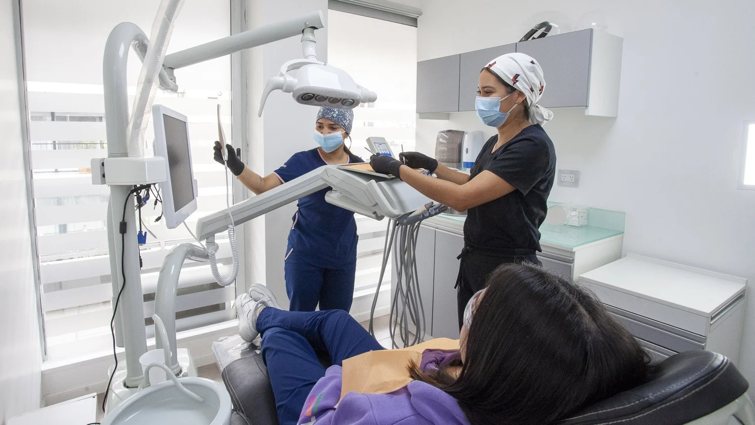Dos odontólogas realizando una consulta dental integral con equipamiento moderno a una paciente en Pineda Dental Studio, Recoleta