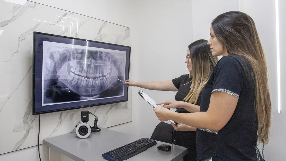Odontólogas analizando una radiografía panorámica digital en pantalla grande para el diagnóstico de un paciente en Pineda Dental Studio, Recoleta.