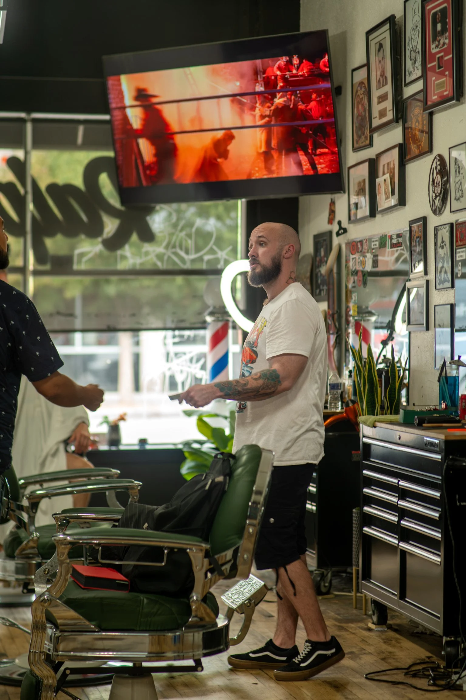 Tony standing behind barber chair handing something to a customer.