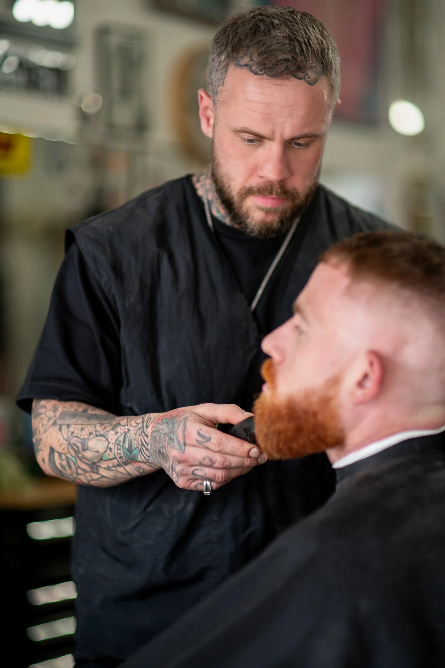 Ralph trimming a customer's beard. The customer has a red beard and mustache.