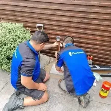 Two electricians from Linc Electrical are working on an outdoor electrical installation