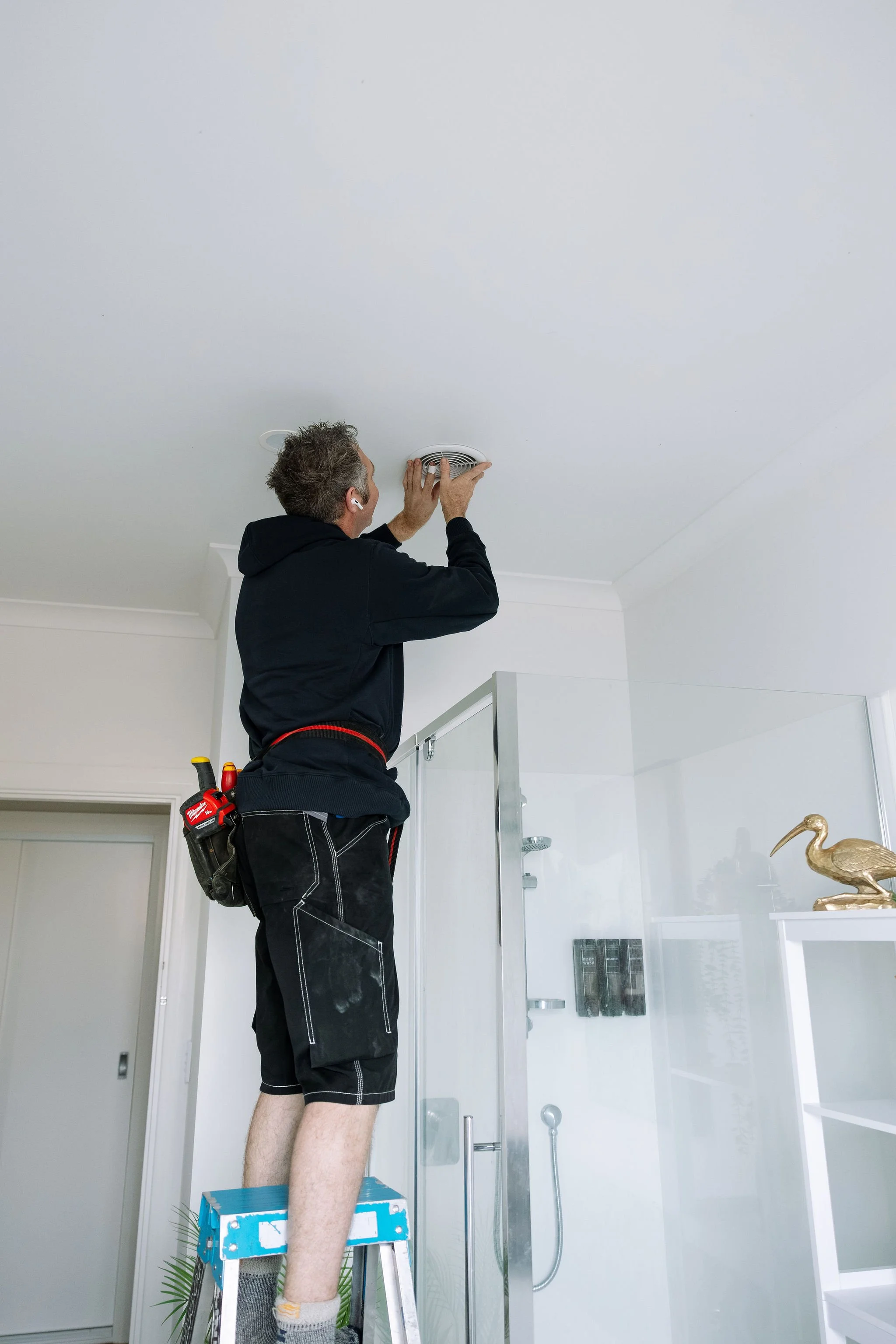 Electrician installing a bathroom ceiling light in a new home